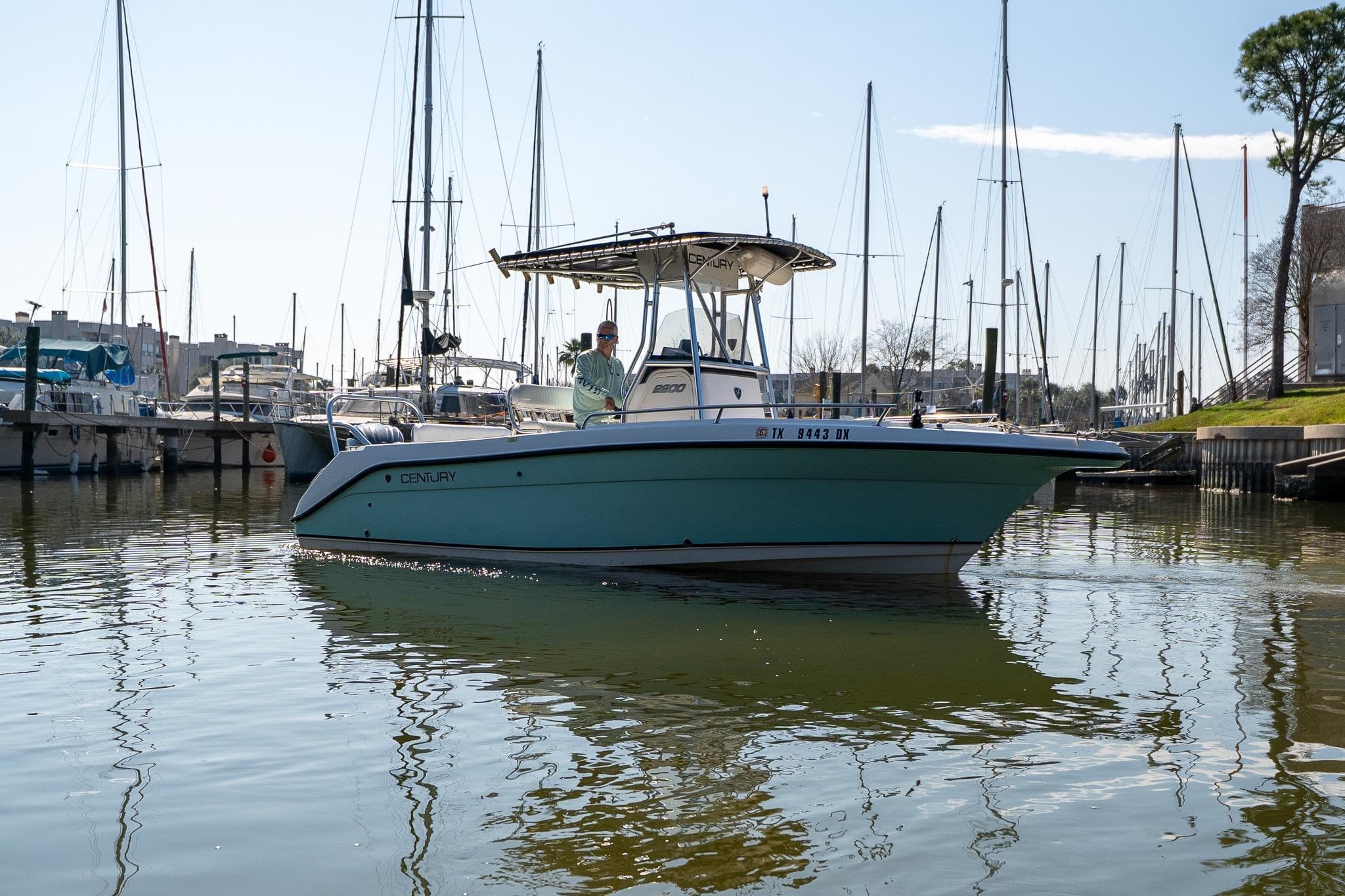 2007 Century 2200 Center Console boat on calm marina waters with sailboats in background.