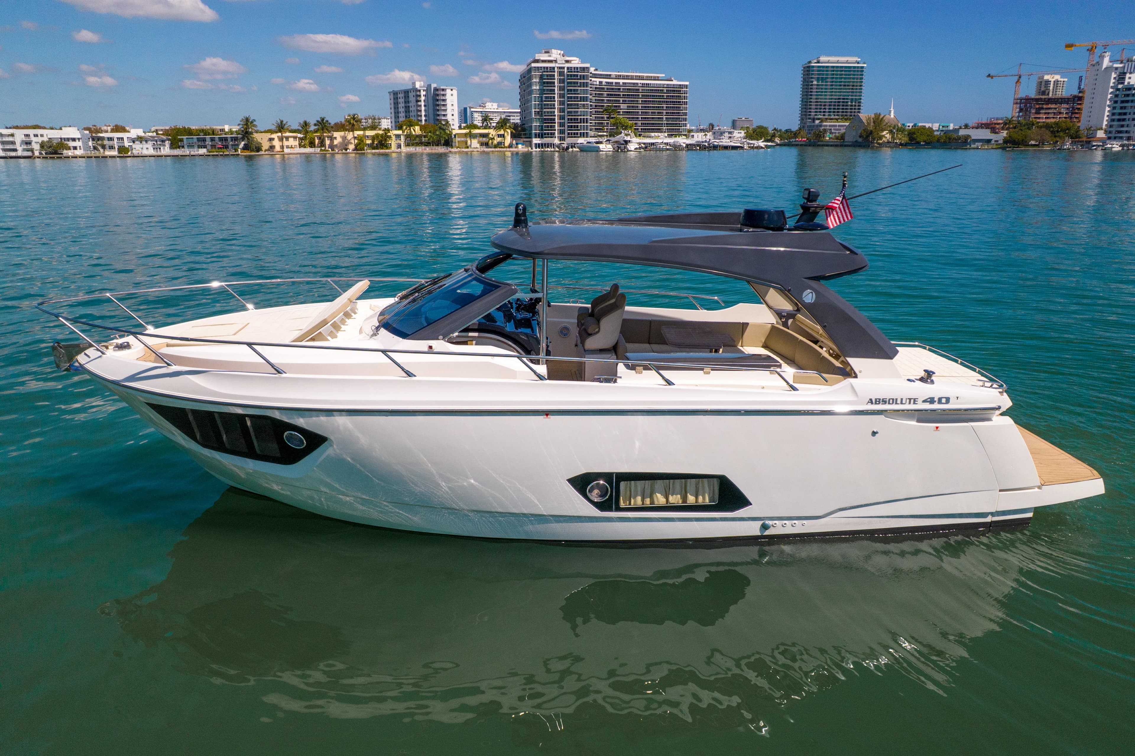 2017 Absolute 40 STL yacht on calm water with city skyline backdrop.