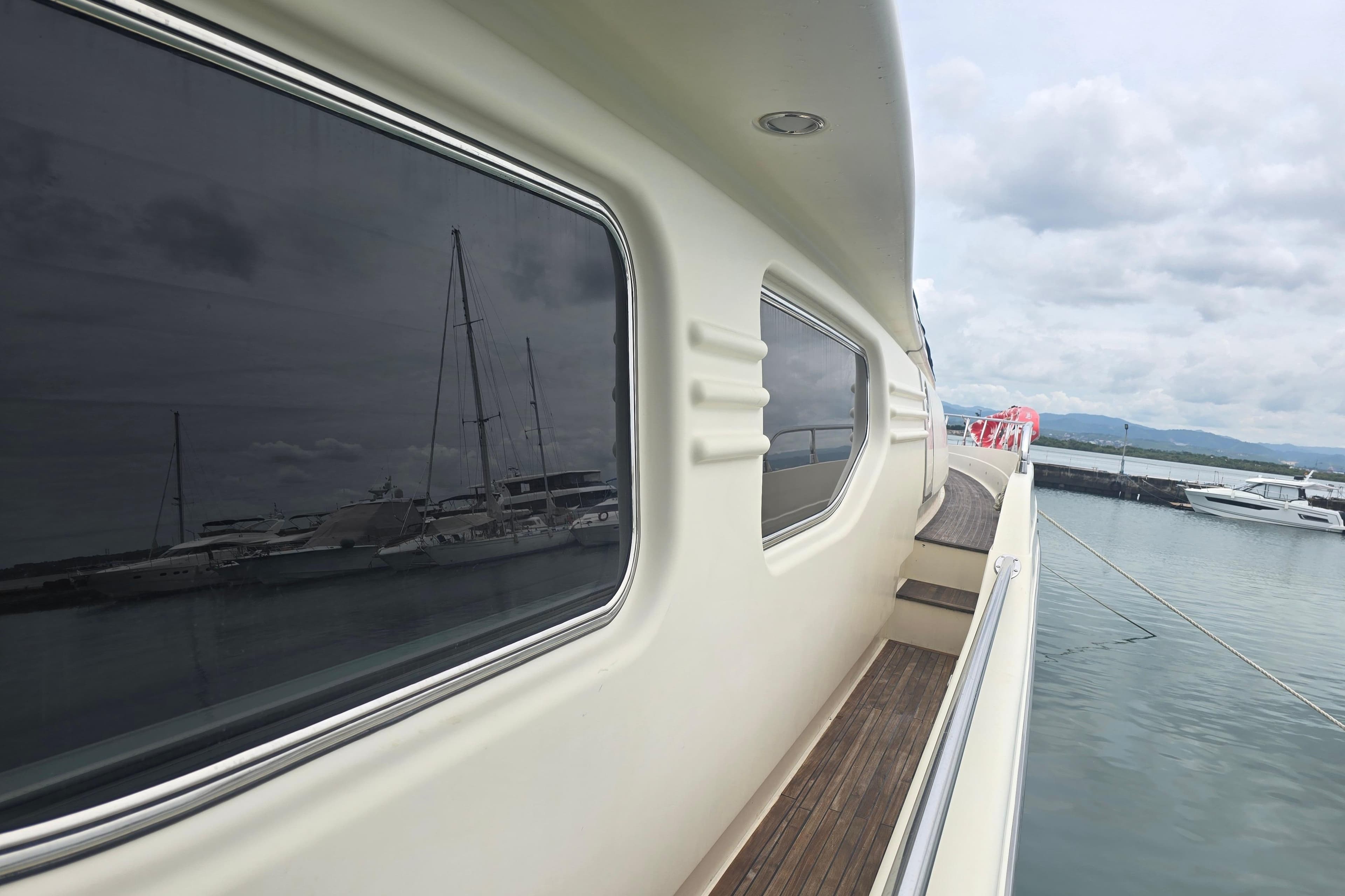 1998 Posillipo Technema 80 yacht docked, reflecting marina view on windows.