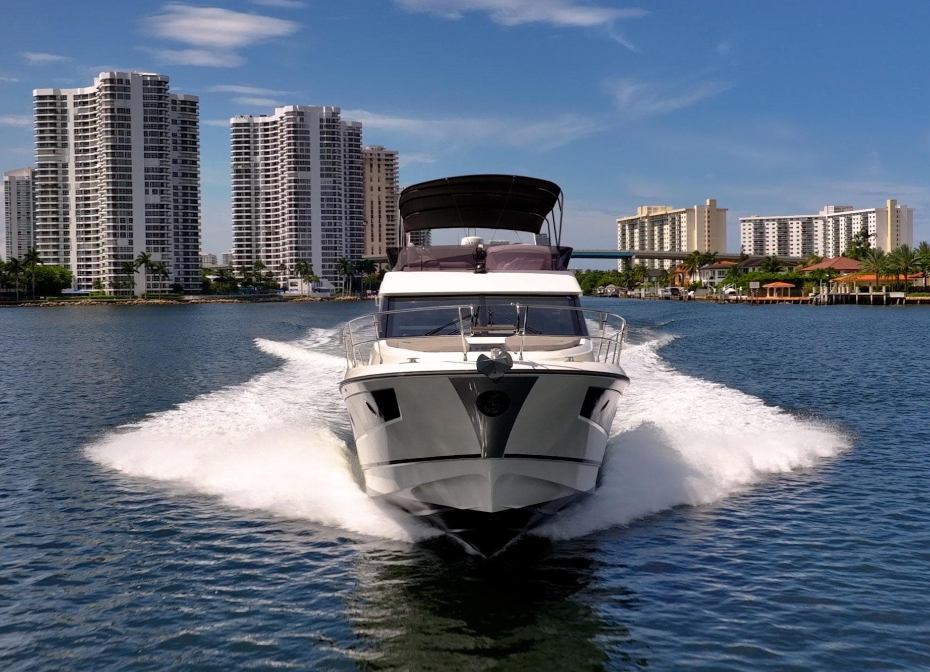 2021 Beneteau Monte Carlo 52 yacht cruising near modern city skyline.