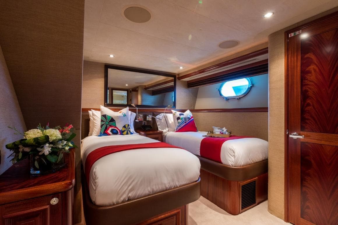 Luxurious twin bedroom on 2008 Westport 130 yacht, featuring elegant decor and porthole window.