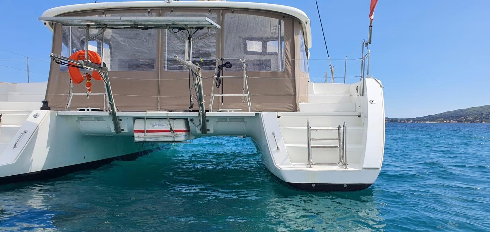 Lagoon 450 F catamaran, 2016 model, anchored in clear blue water, rear view.