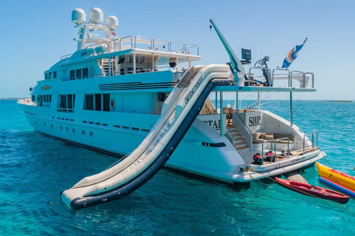Luxurious 1988 Van Mill 143 Tri-Deck Motor Yacht with slide, anchored in clear blue waters.