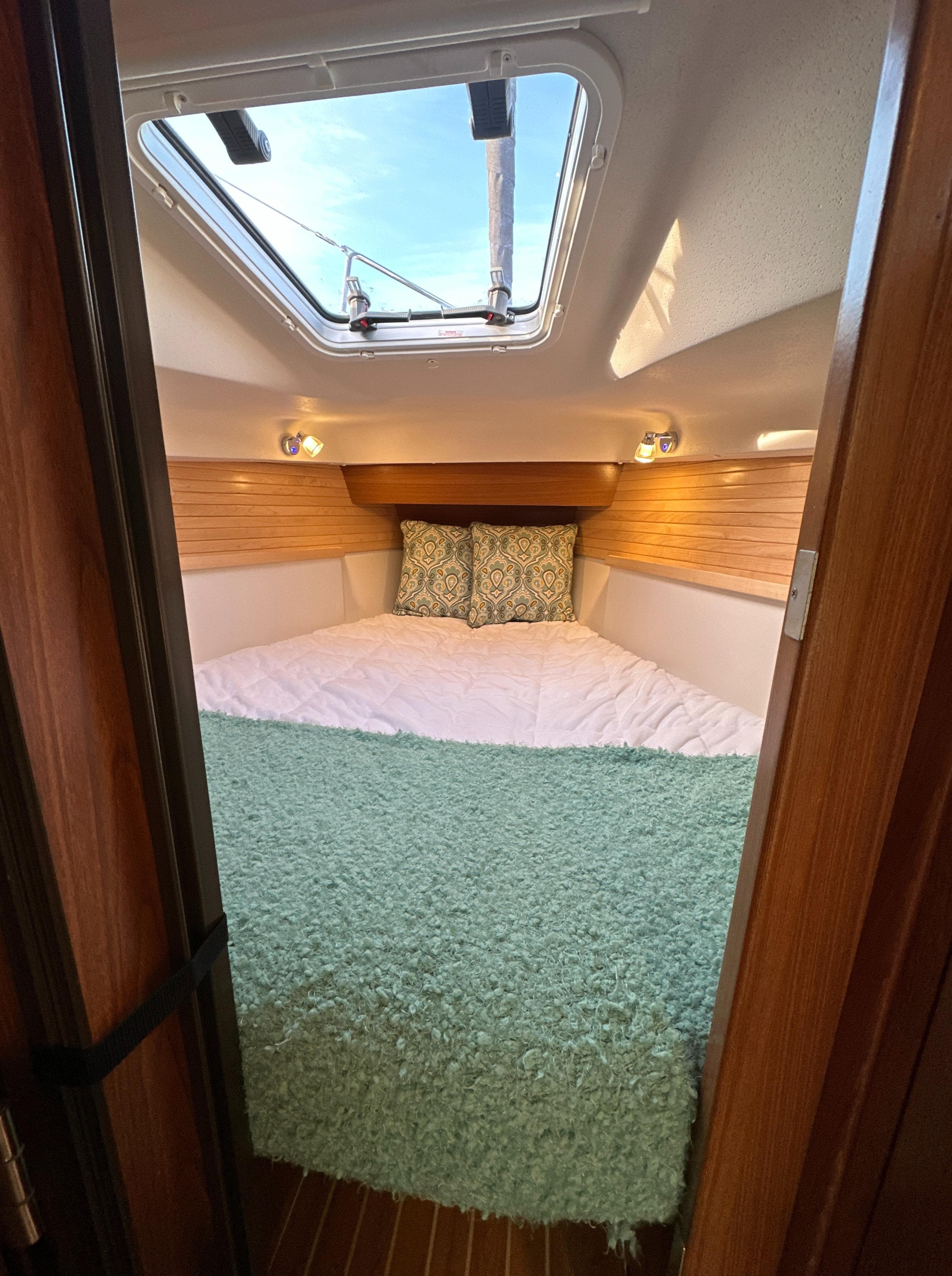 Cozy cabin interior of 2023 Catalina 315 sailboat with skylight and bedding.