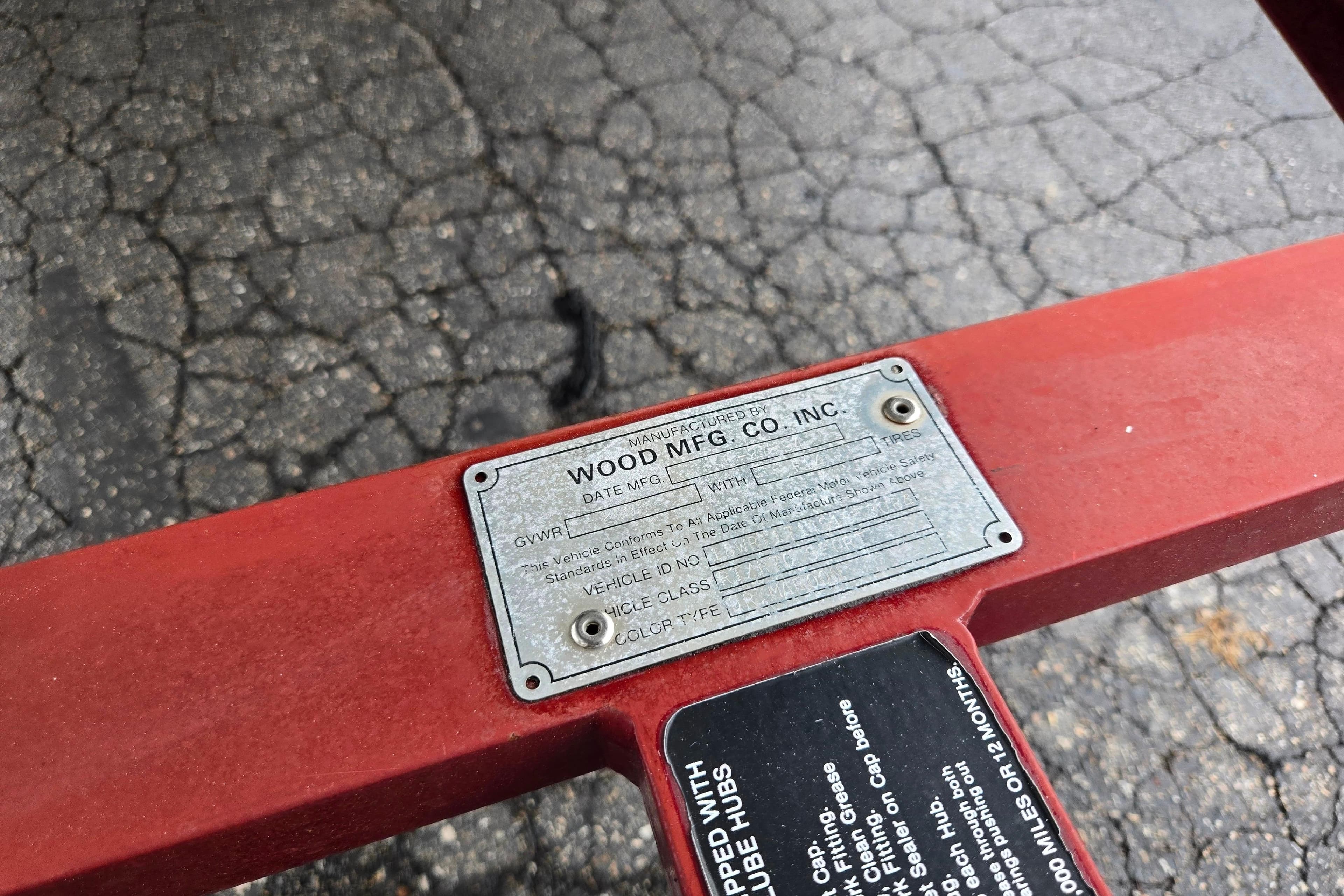 Metal identification plate on red Ranger R72 Sport, 1995 model, on cracked asphalt surface.