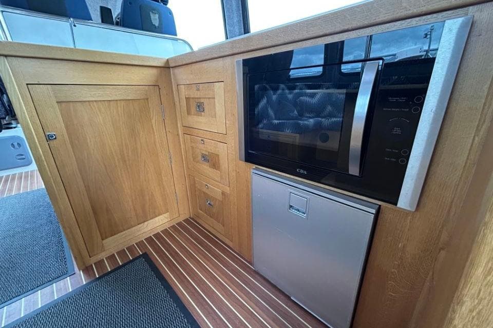 Interior of 2018 Redbay Boats 1650 Explorer Cabin RIB with wooden cabinetry and appliances.