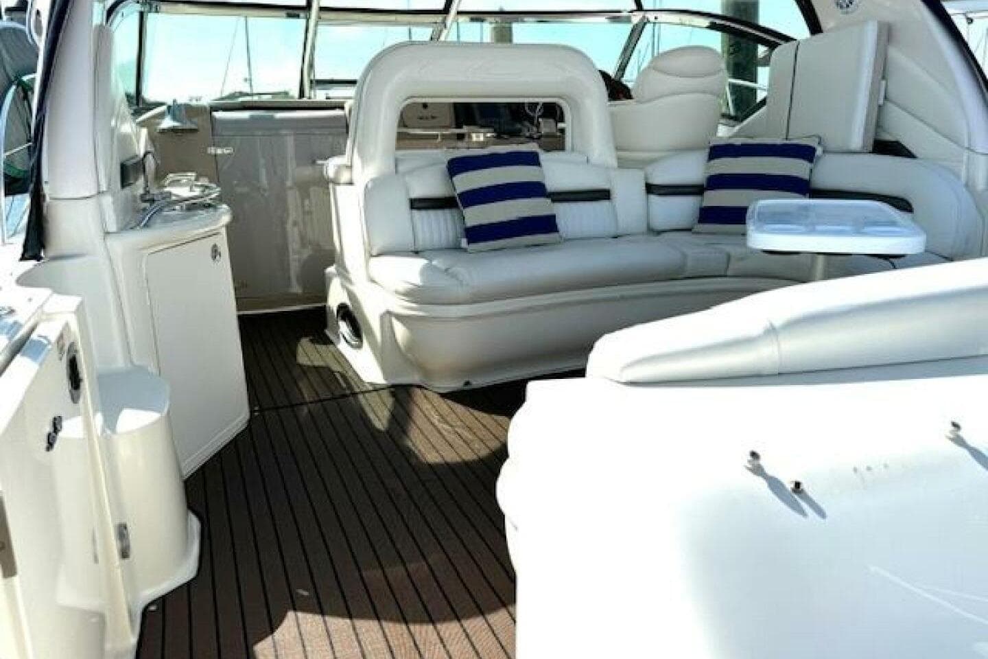 Luxurious interior of 2003 Sea Ray 420 Sundancer yacht with white seating and striped cushions.