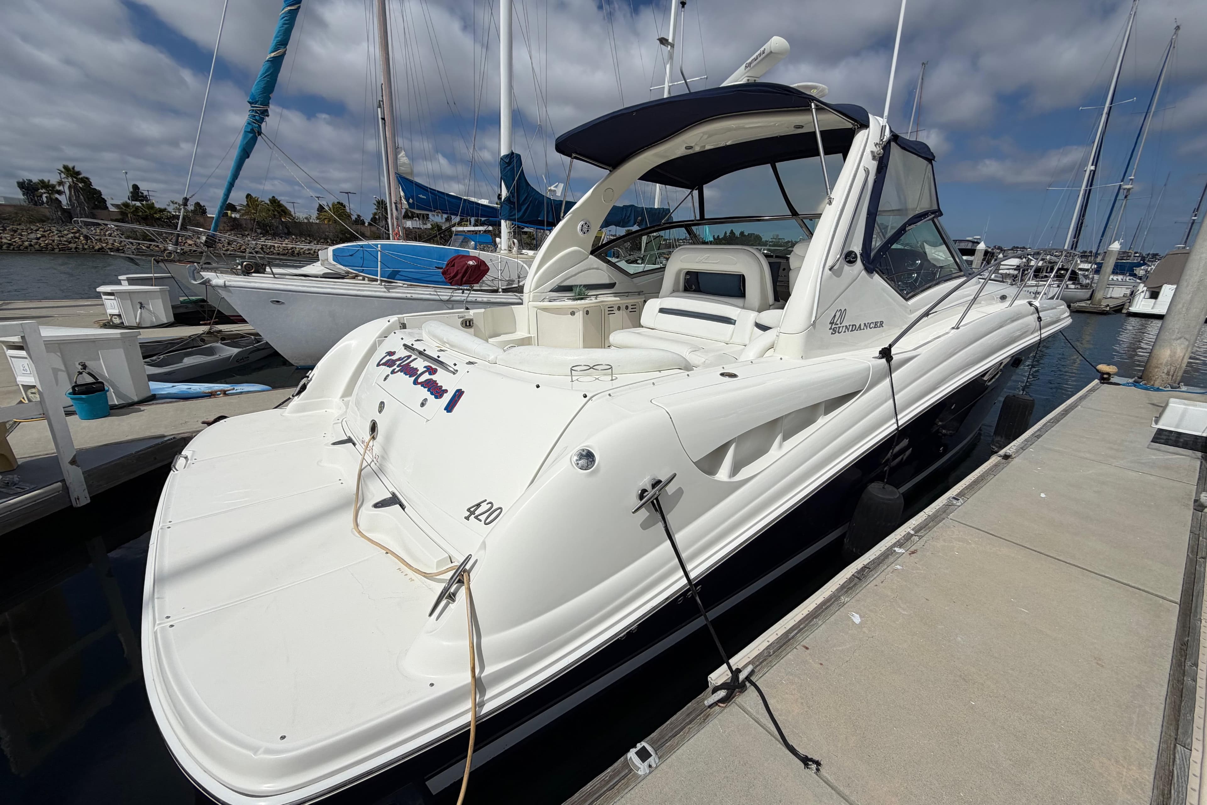 2003 Sea Ray 420 Sundancer yacht docked at marina under cloudy sky.