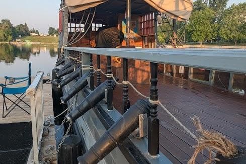 Custom 2016 pirate ship docked by a serene lake, featuring decorative cannons and wooden deck.