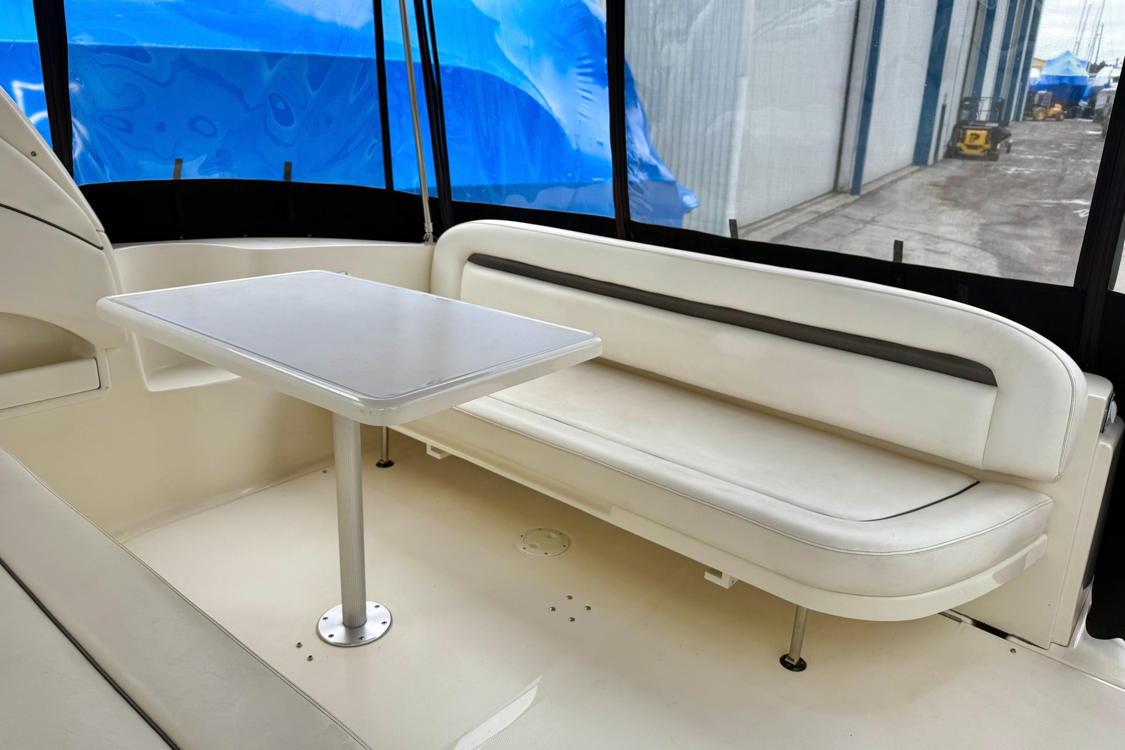 2004 Searay 360 Sundancer interior with white seating and table, docked near blue tarps.