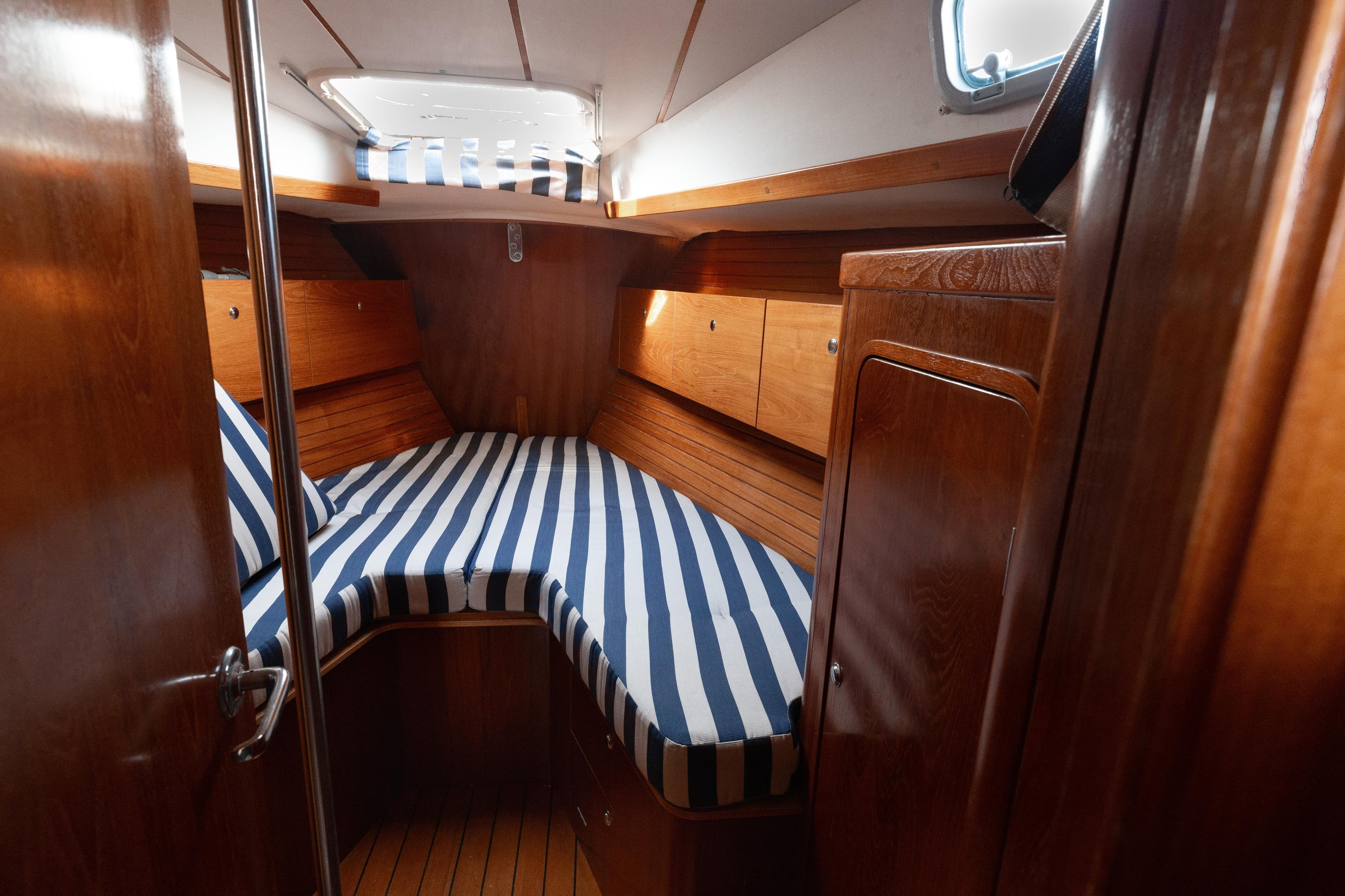 Cozy cabin interior of 1999 Beneteau Oceanis 44 CC with striped bedding.