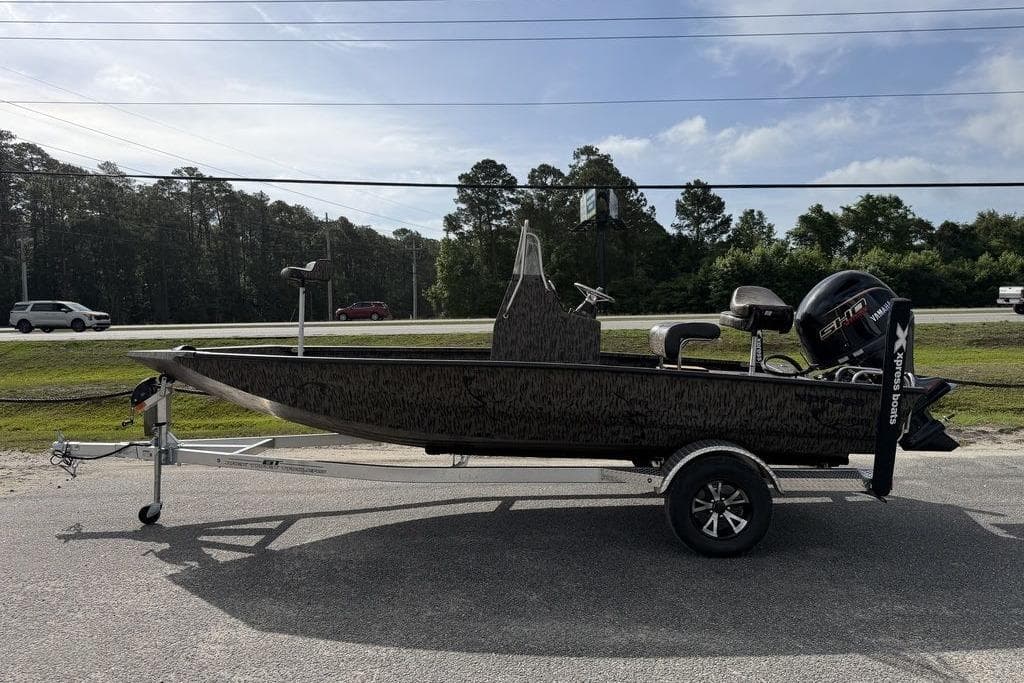 2026 Xpress H190B Bay boat on trailer, parked roadside under clear sky.