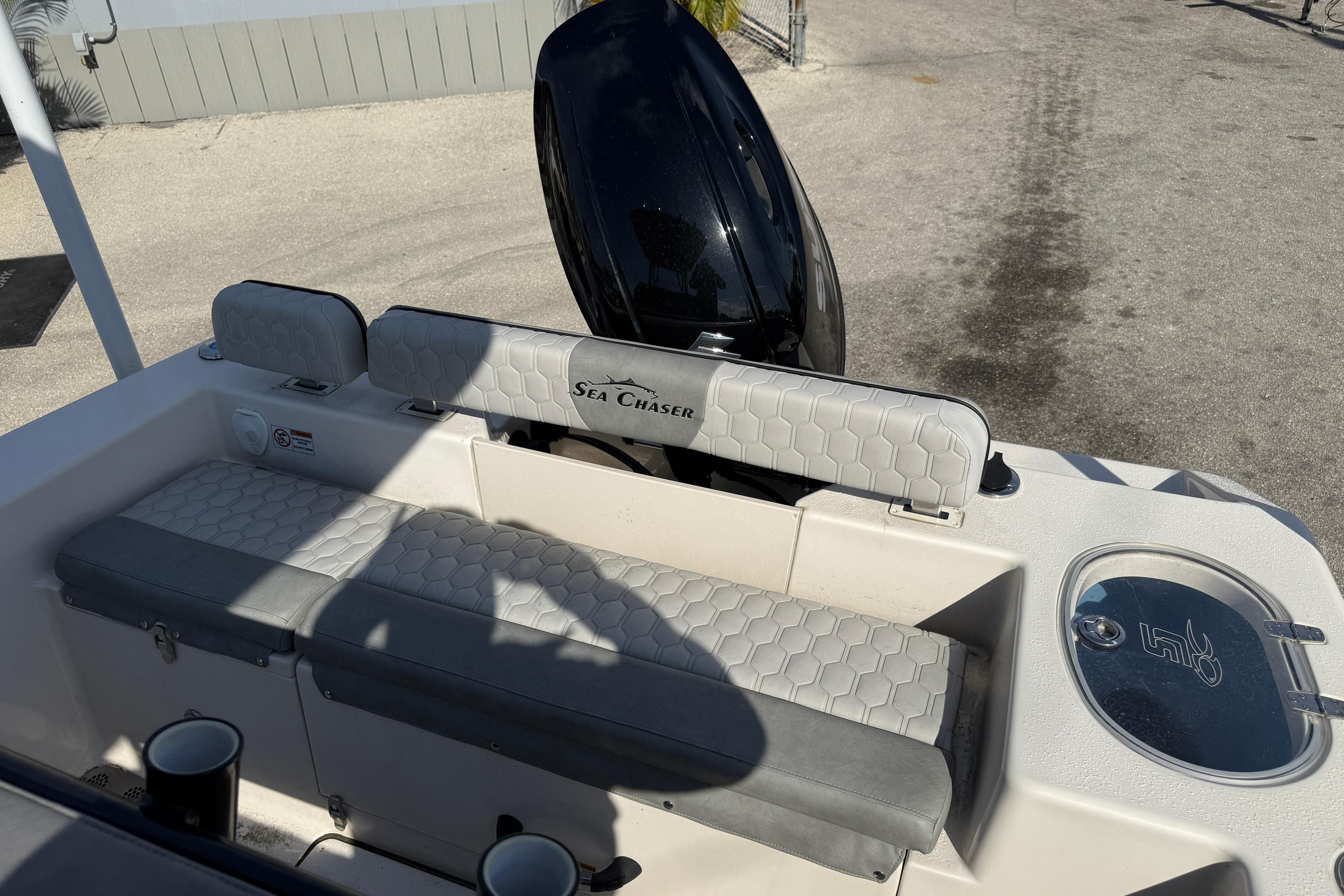 2025 Sea Chaser 22 HFC boat interior with seating and motor, parked on pavement.