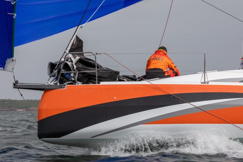 2025 Jeanneau Sun Fast 3300 sailing with vibrant orange and black design.