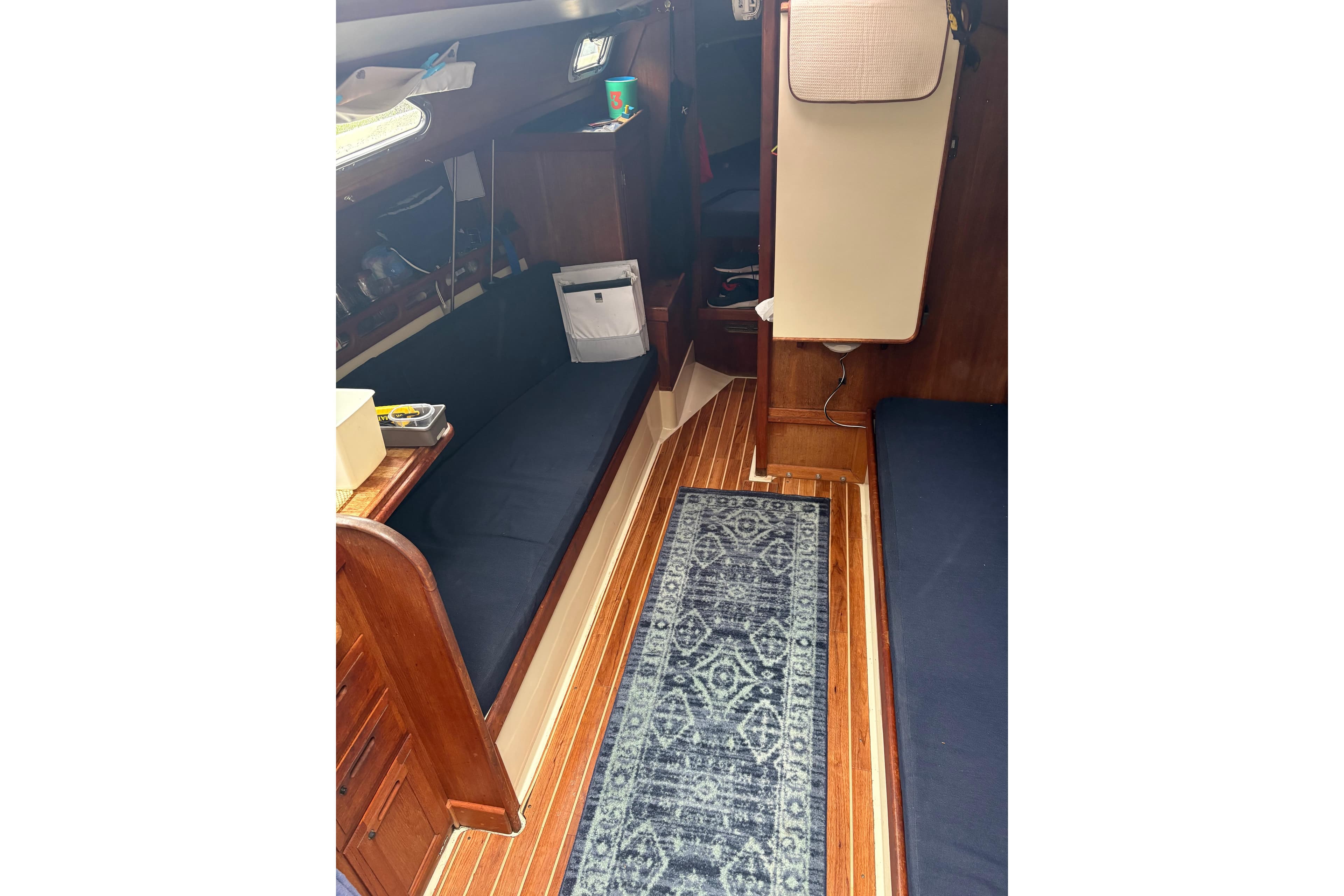 Interior of 1987 Ericson 28/2 sailboat with wooden flooring and blue seating.
