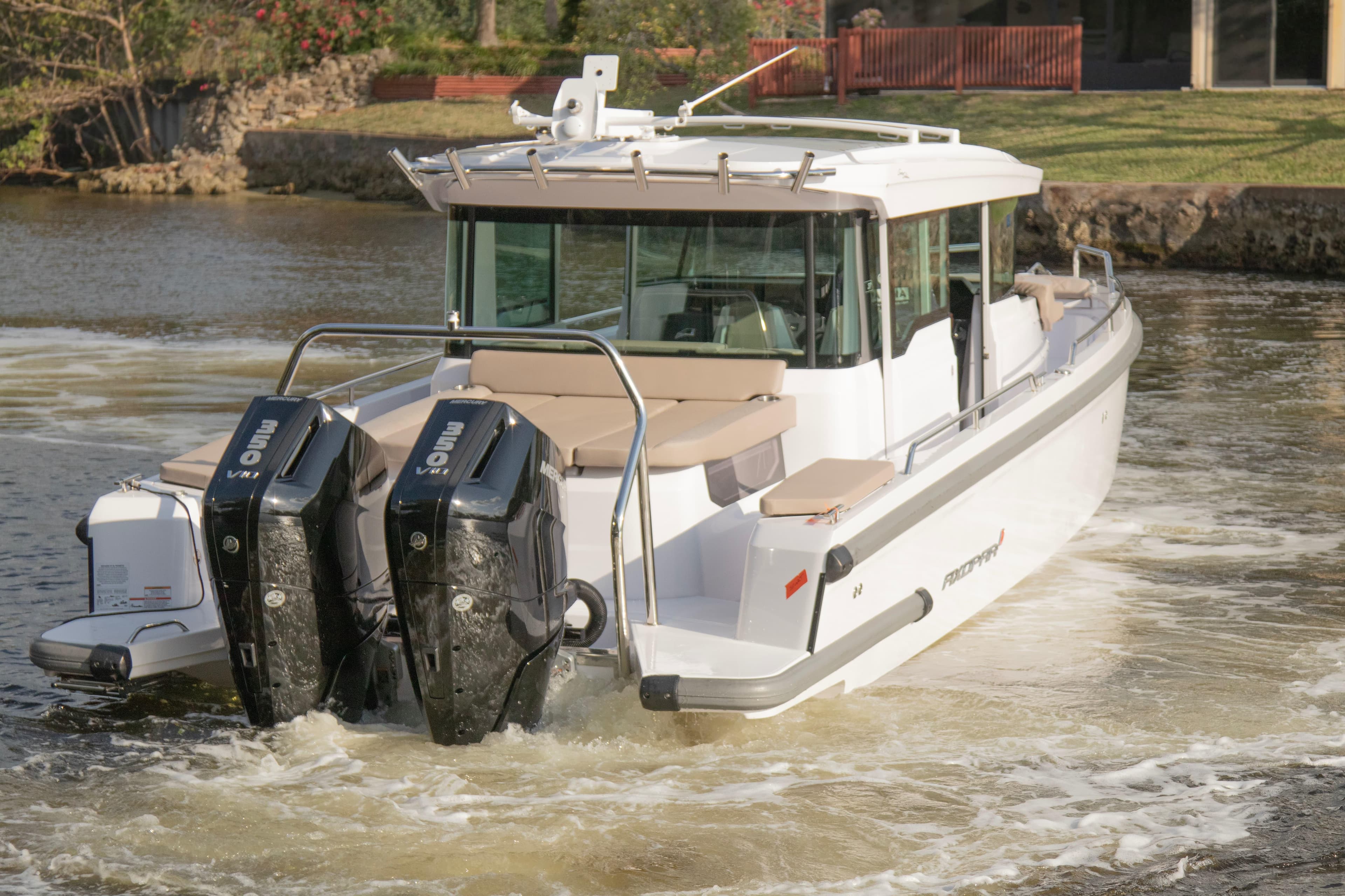 2024 Axopar 37XC CROSS CABIN boat with dual outboard engines on a calm waterway.