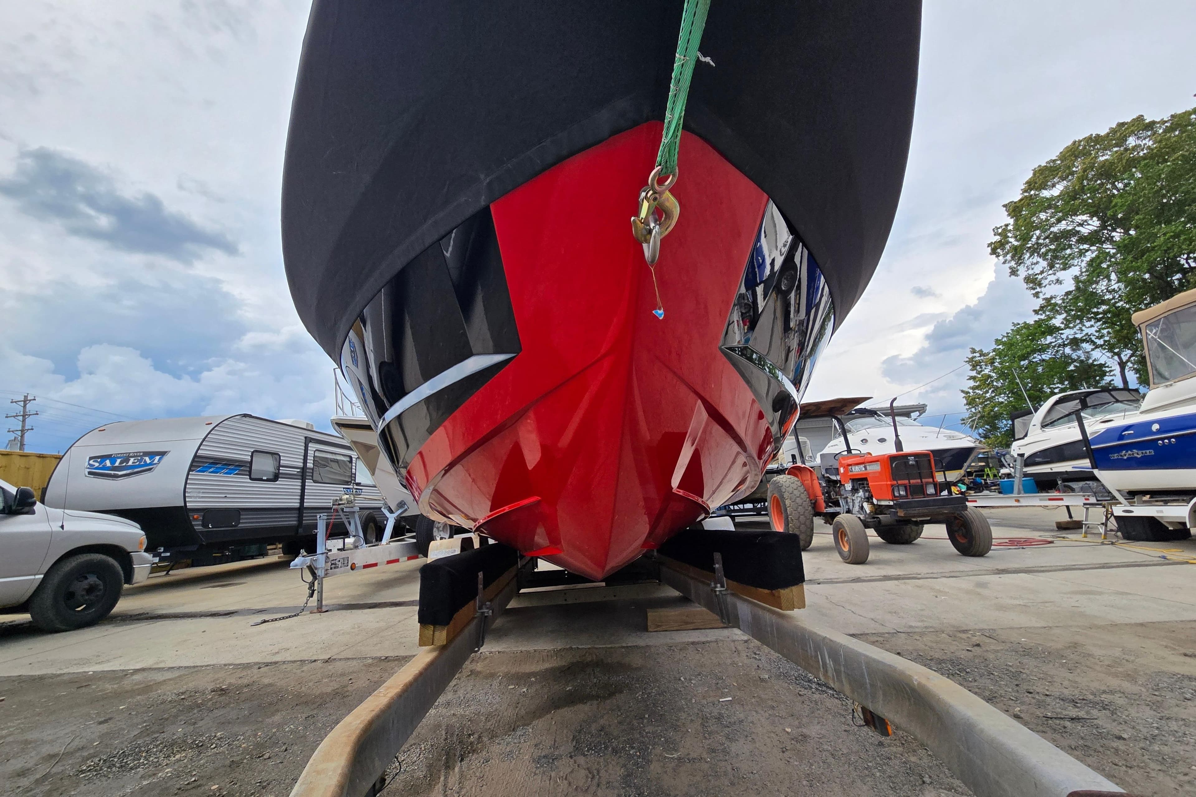 2019 MasterCraft XT25 boat on trailer, vibrant red hull, parked in marina.