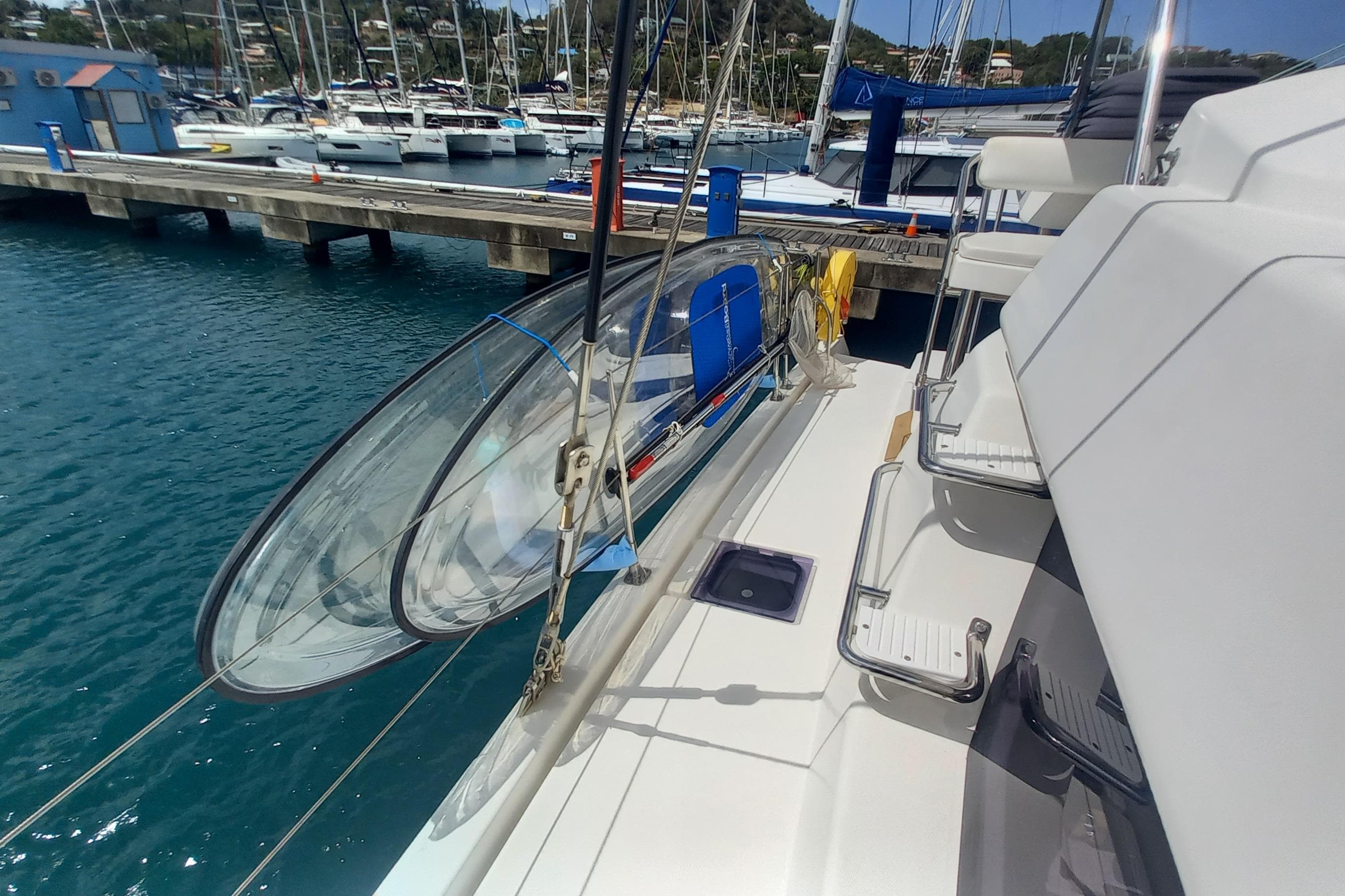 Leopard 45 catamaran docked at marina, featuring kayaks and clear blue water.