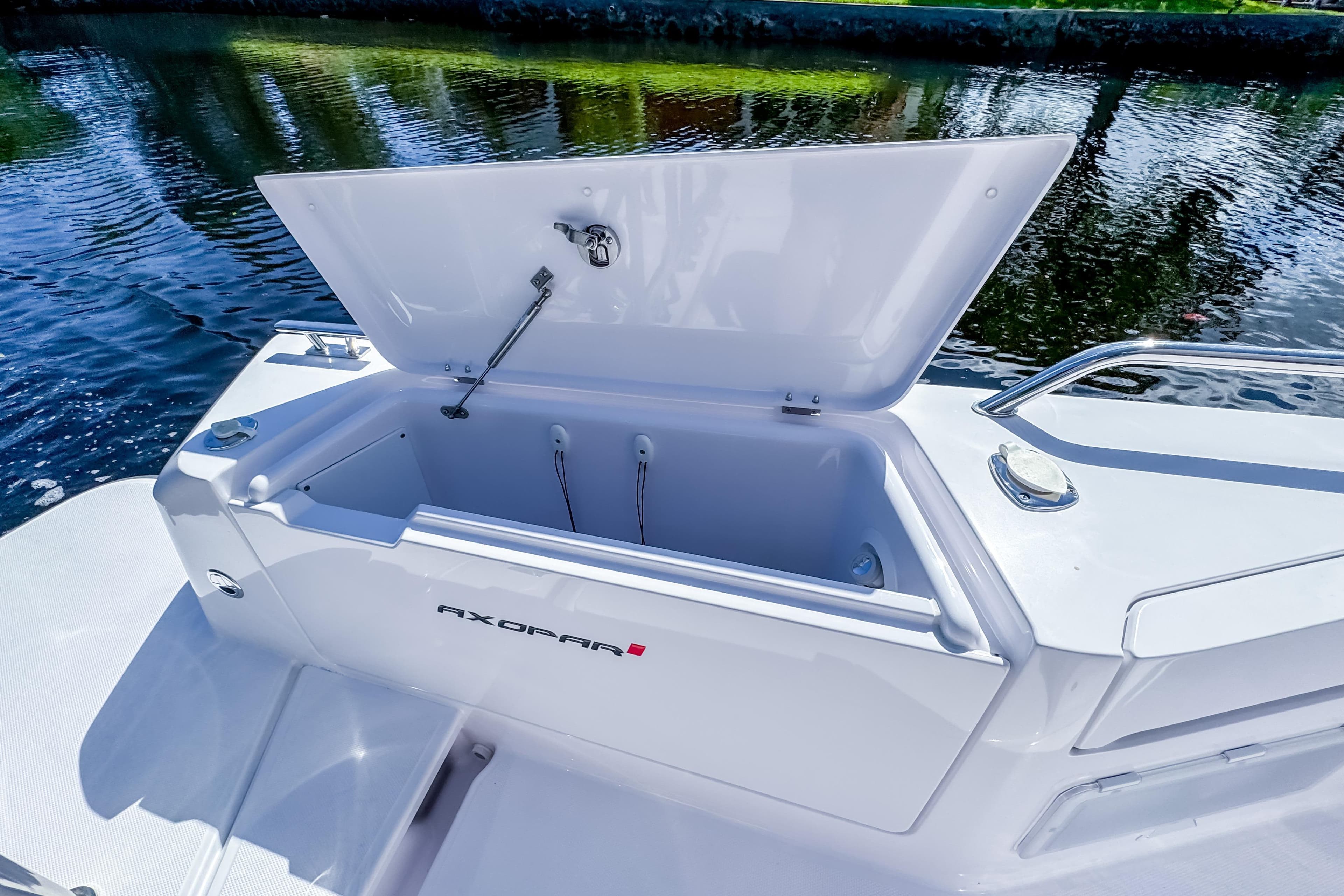 2024 Axopar 37 Sun Top boat with open storage compartment by the water.