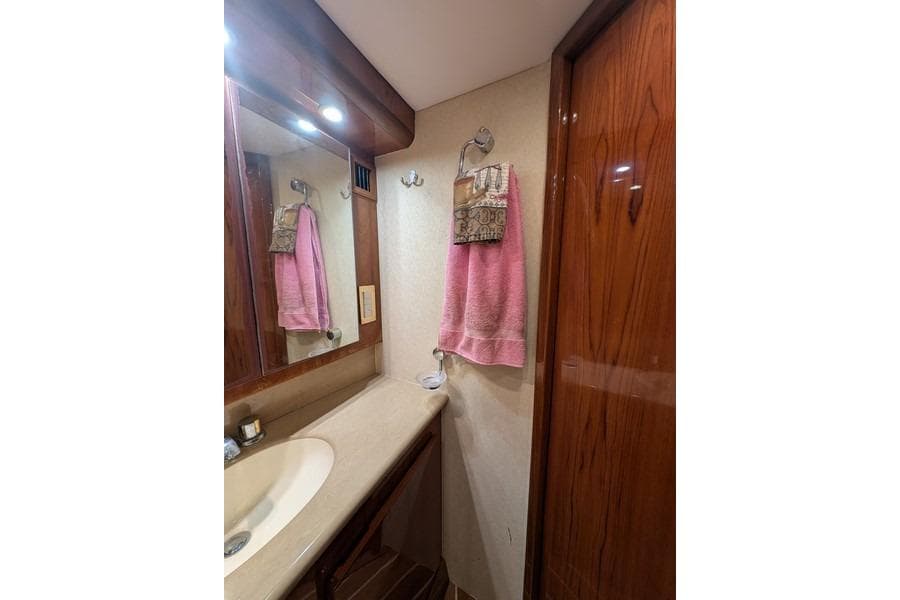 Bathroom interior of 2005 Egg Harbor 43 SportYacht with wooden cabinetry and pink towel.