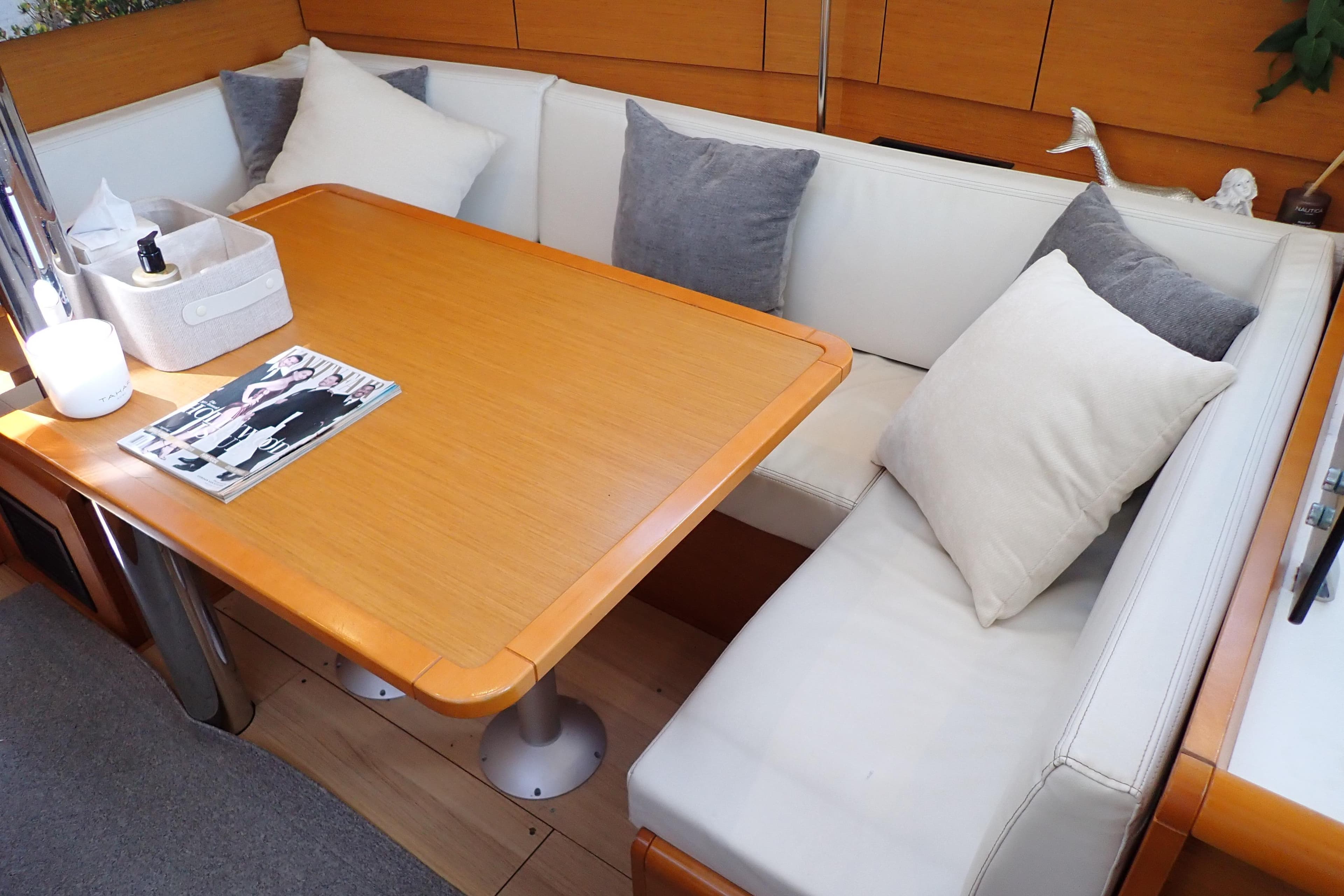 Cozy interior of 2018 Jeanneau Sun Odyssey 389 with cushioned seating and wooden table.