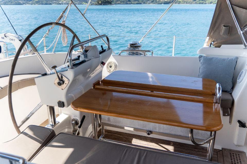 Cockpit of 2008 Discovery 55 yacht with wooden table and steering wheel, overlooking the sea.