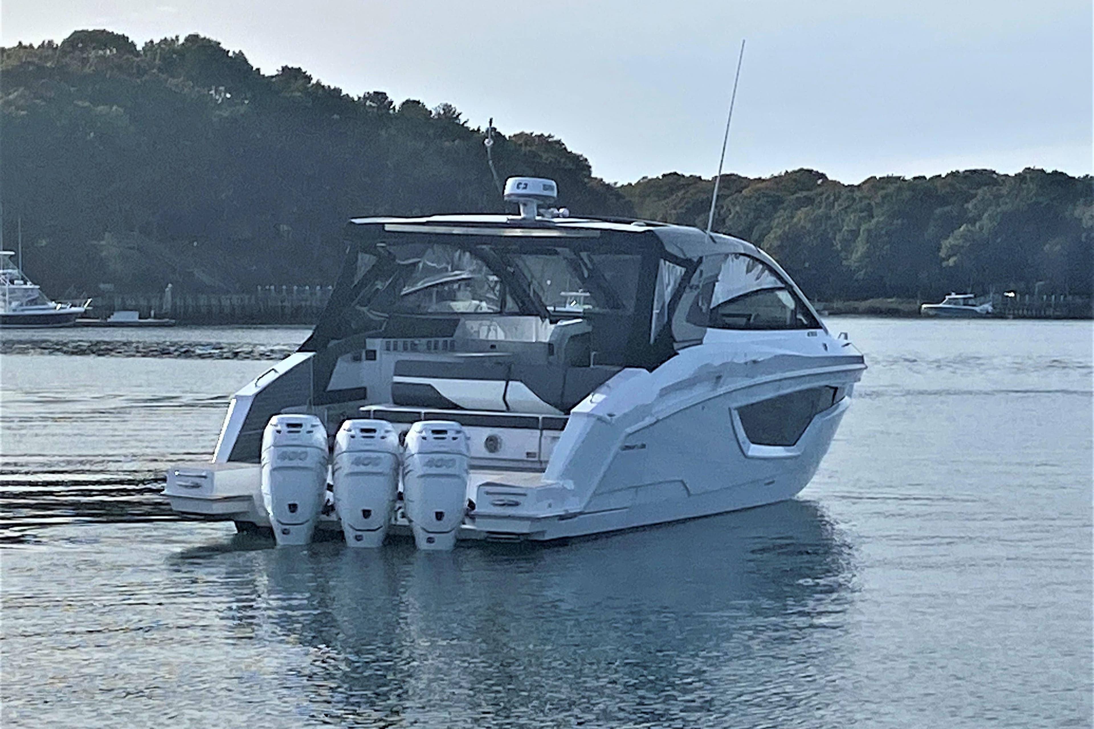 2026 Cruisers Yachts 42 GLS OB on serene water with triple outboard engines.