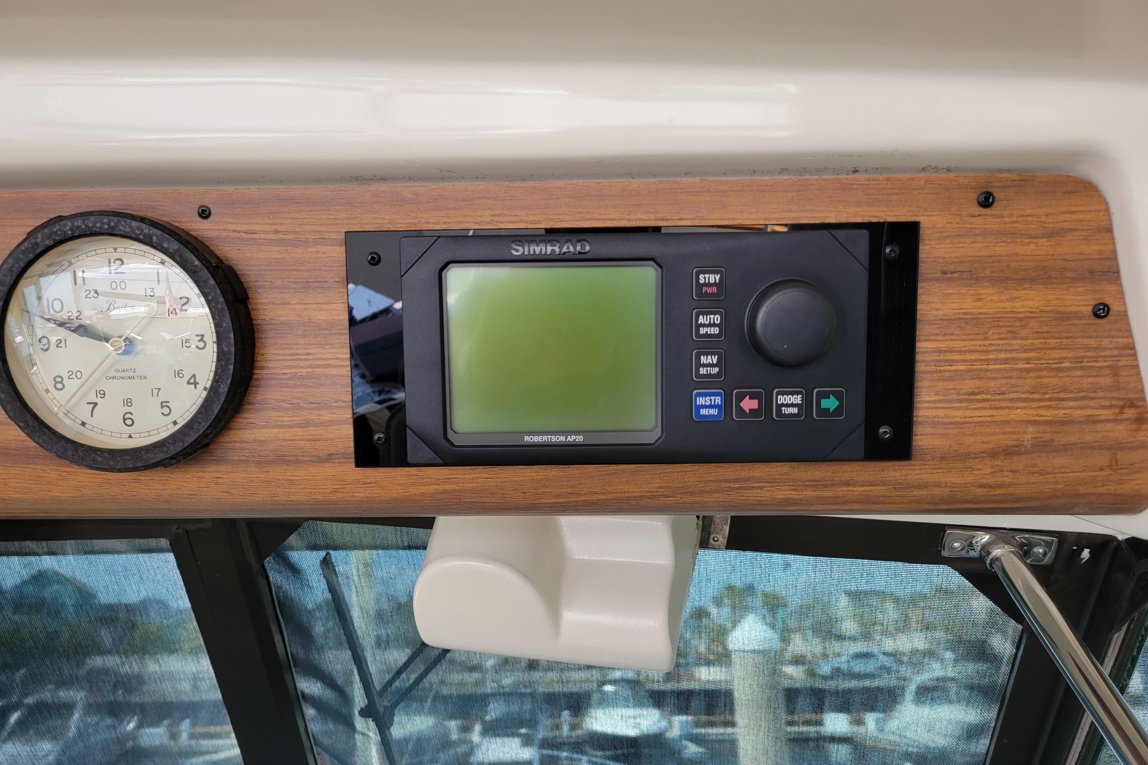 1977 Hatteras 43 Double Cabin dashboard with clock and Simrad navigation system.