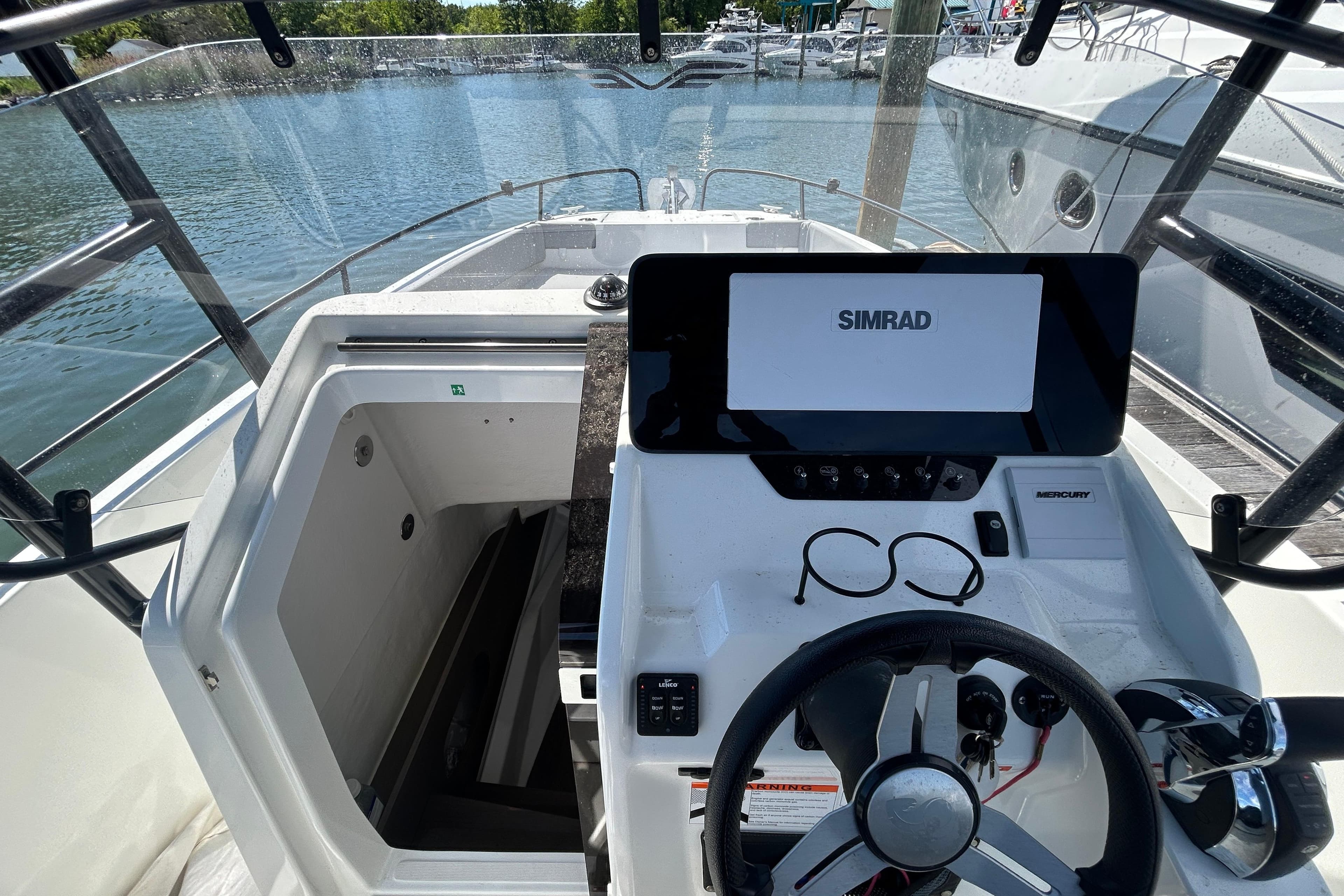 2023 Beneteau Flyer 8 SPACEdeck helm with Simrad display and steering wheel, docked by water.