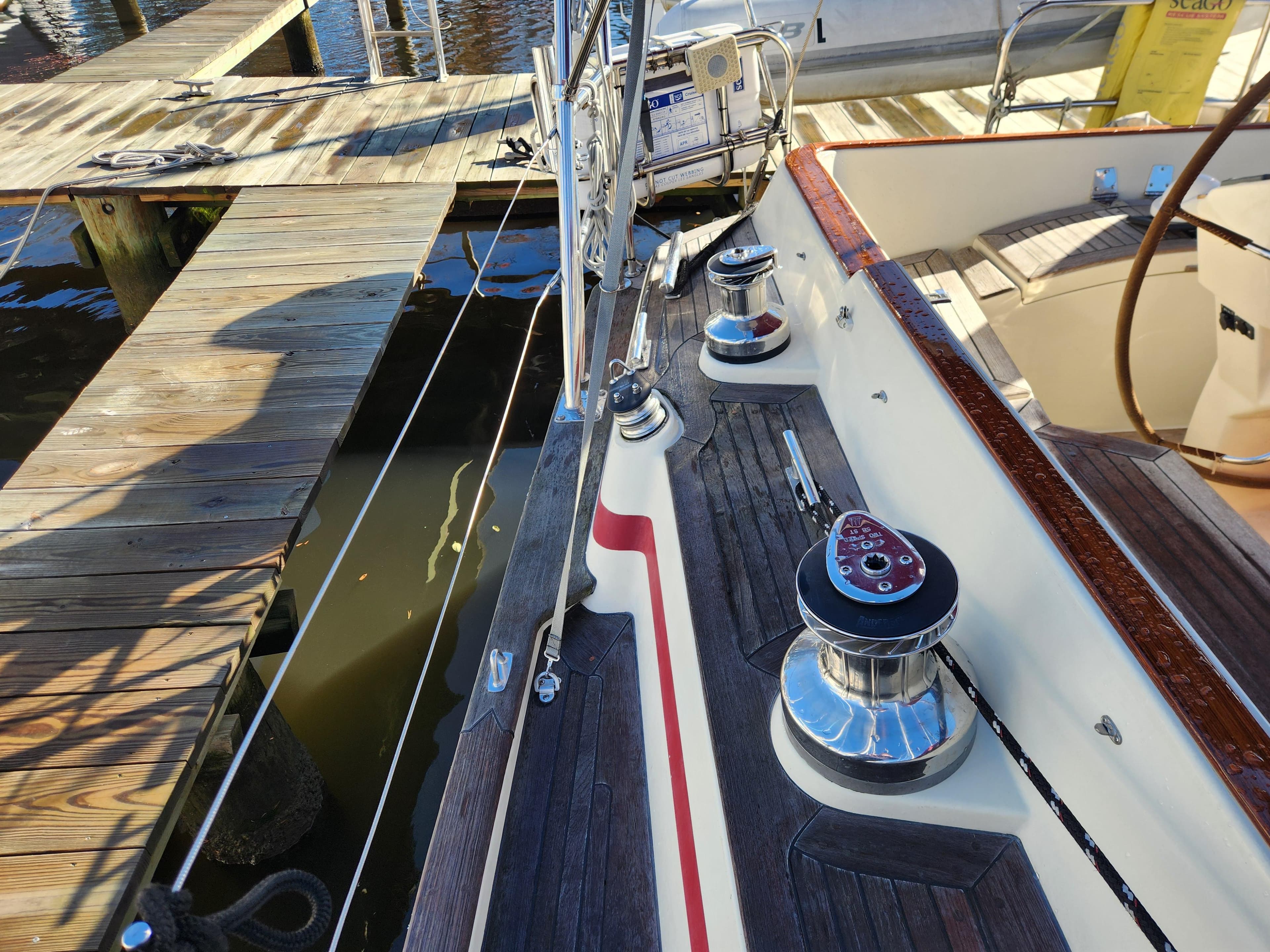 Sailboat deck with winches, Regina 43 model, docked at a wooden pier.