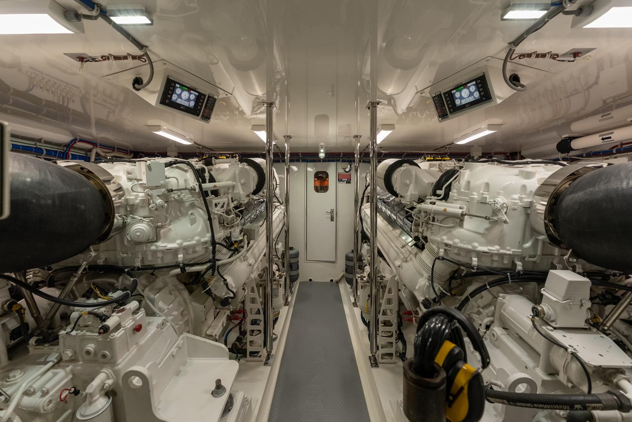Engine room of 2018 Hatteras GT70 yacht, featuring dual engines and control panels.