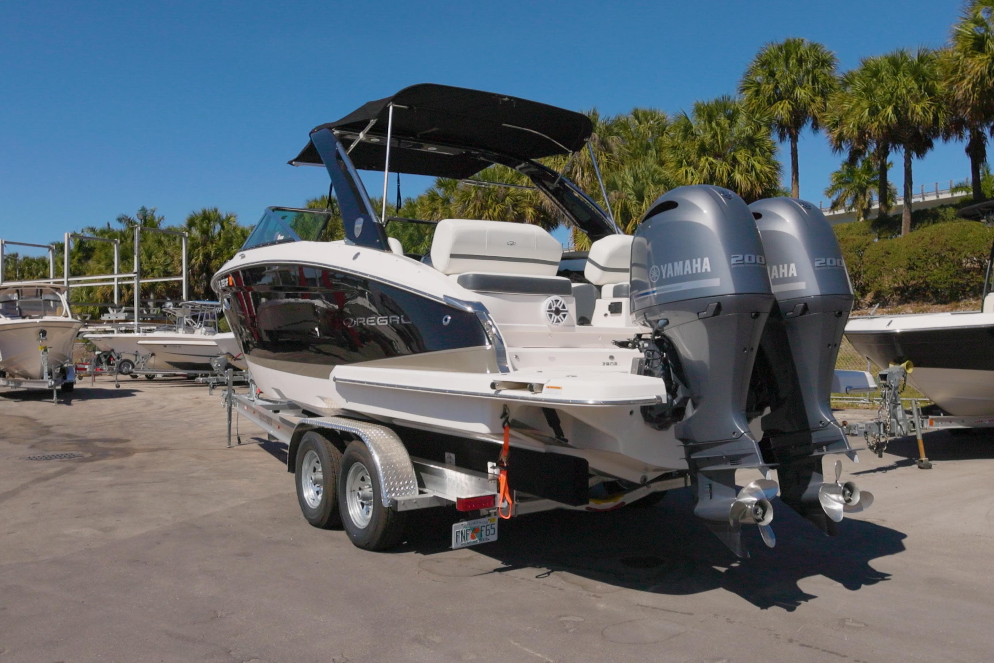 2017 Regal 29 OBX boat with dual Yamaha engines on a trailer, surrounded by palm trees.