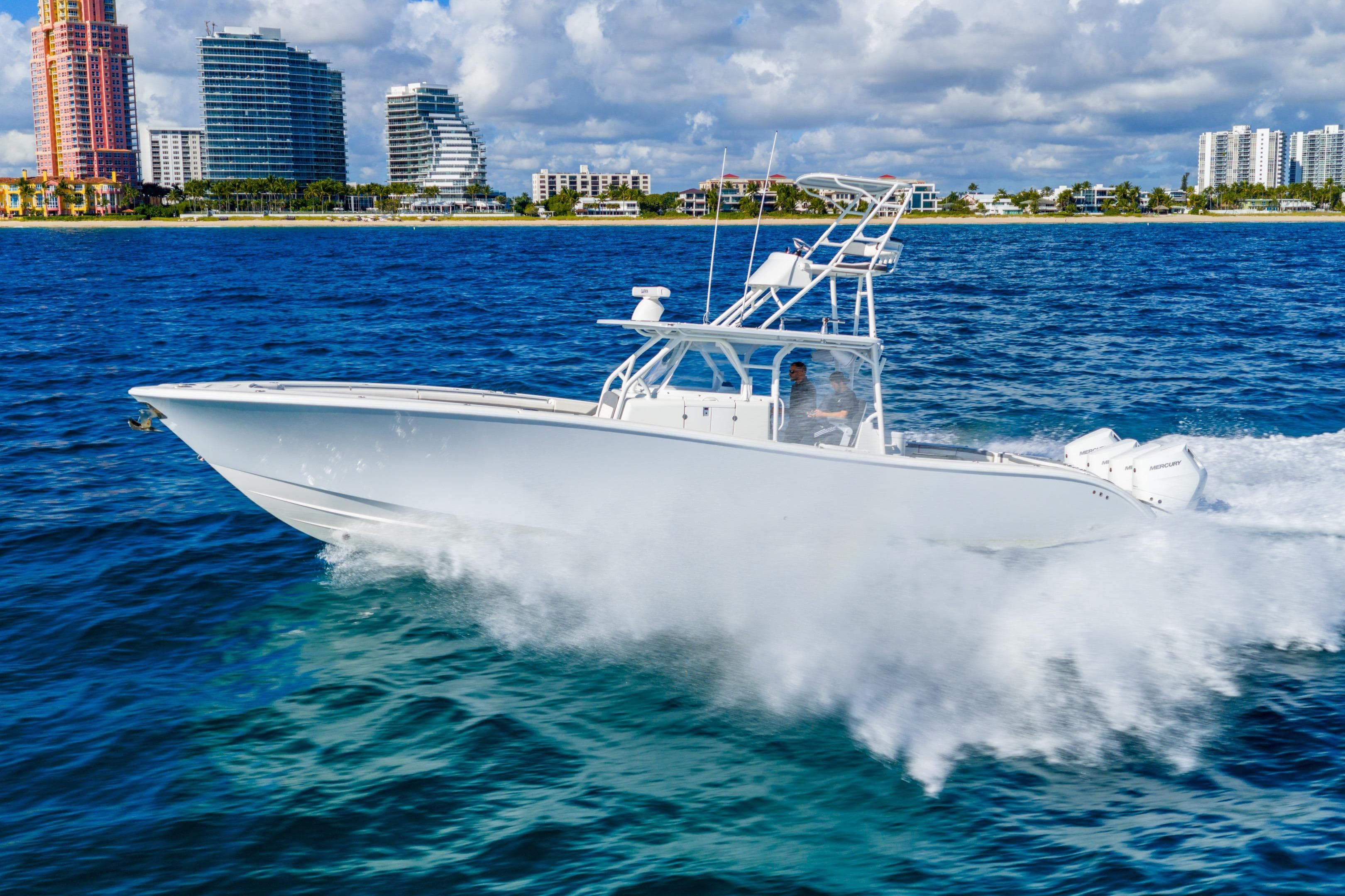 2015 Yellowfin 42 Offshore boat cruising on blue ocean near city skyline.