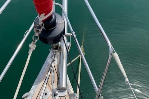 Bow of 1981 Nautor Swan 51 sailboat with red sail cover on calm water.