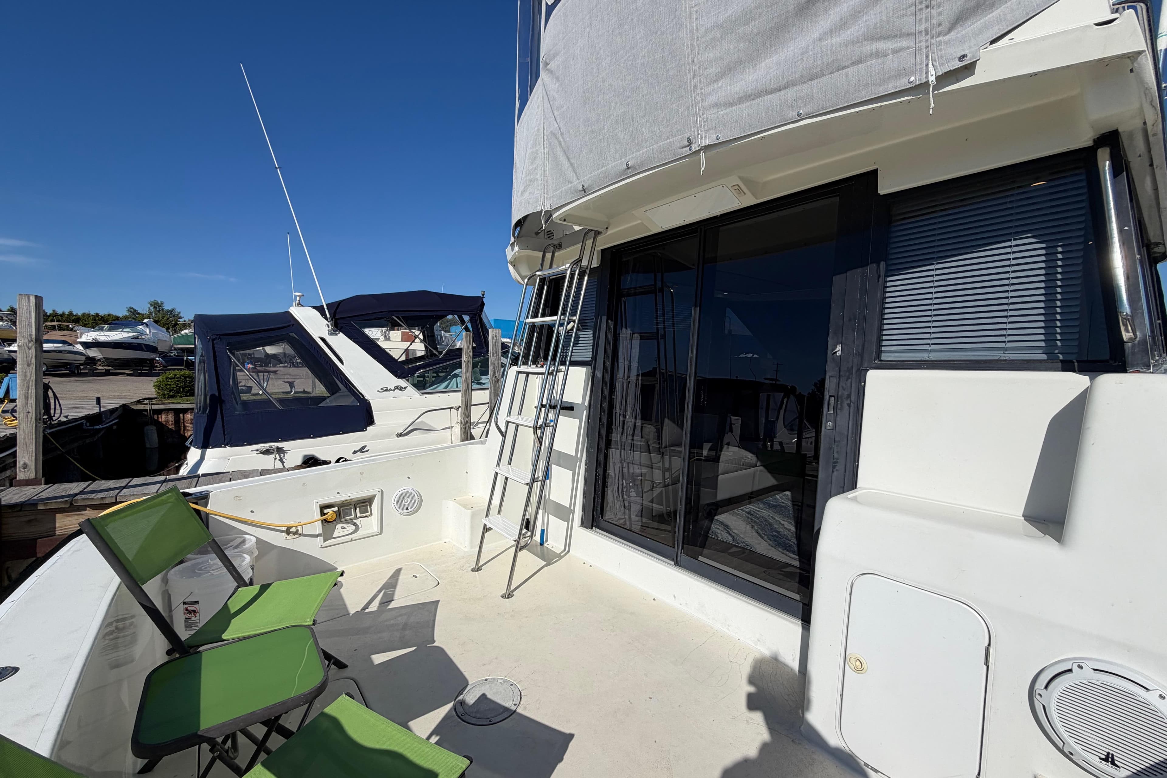 1995 Silverton 37 Convertible yacht deck with green chairs and ladder.
