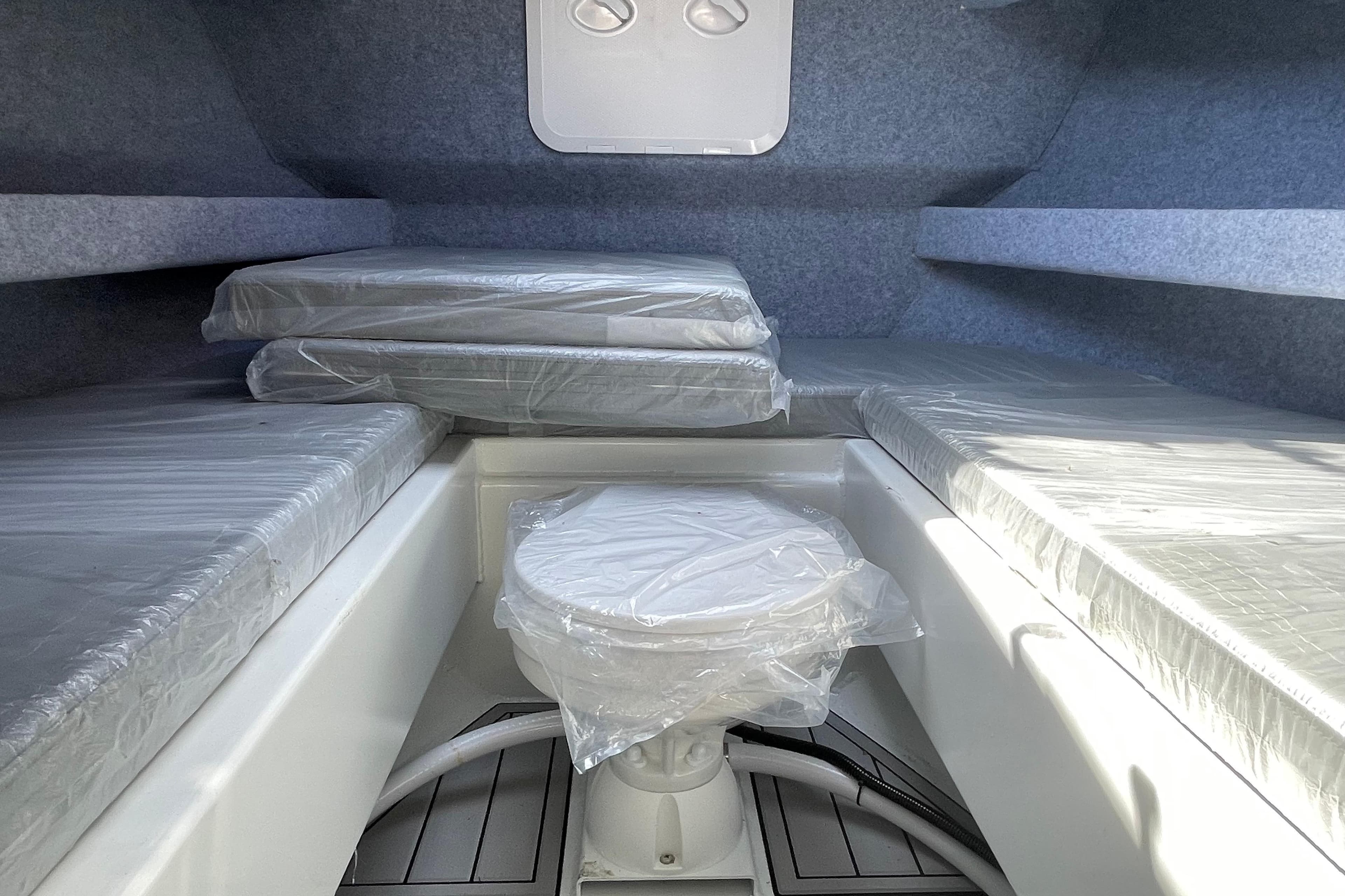 Interior of 2025 Custom Aluminum 7.5 Profisher boat with cushioned seating and compact toilet.