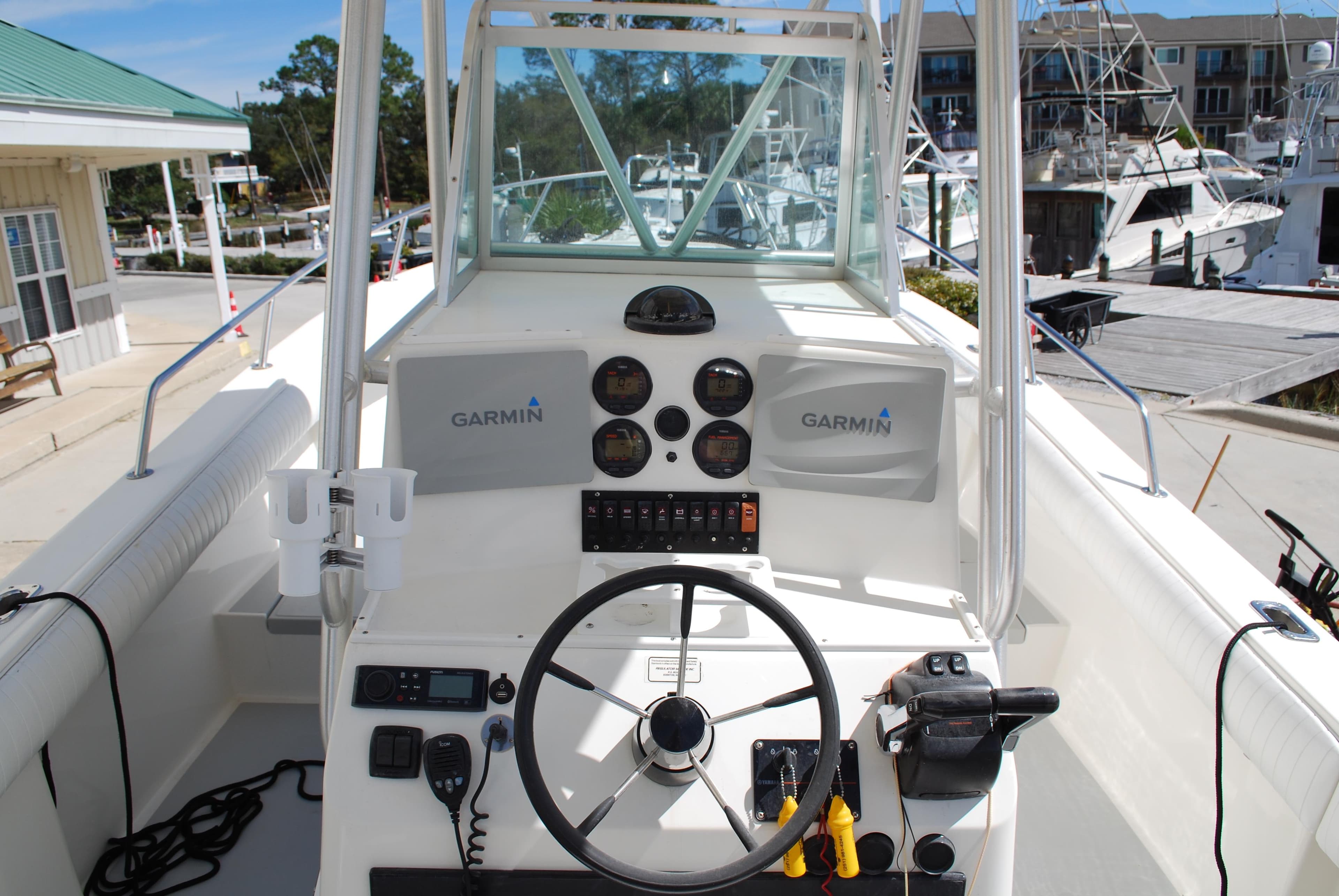 1996 Regulator 26 Classic boat helm with Garmin electronics at a marina.