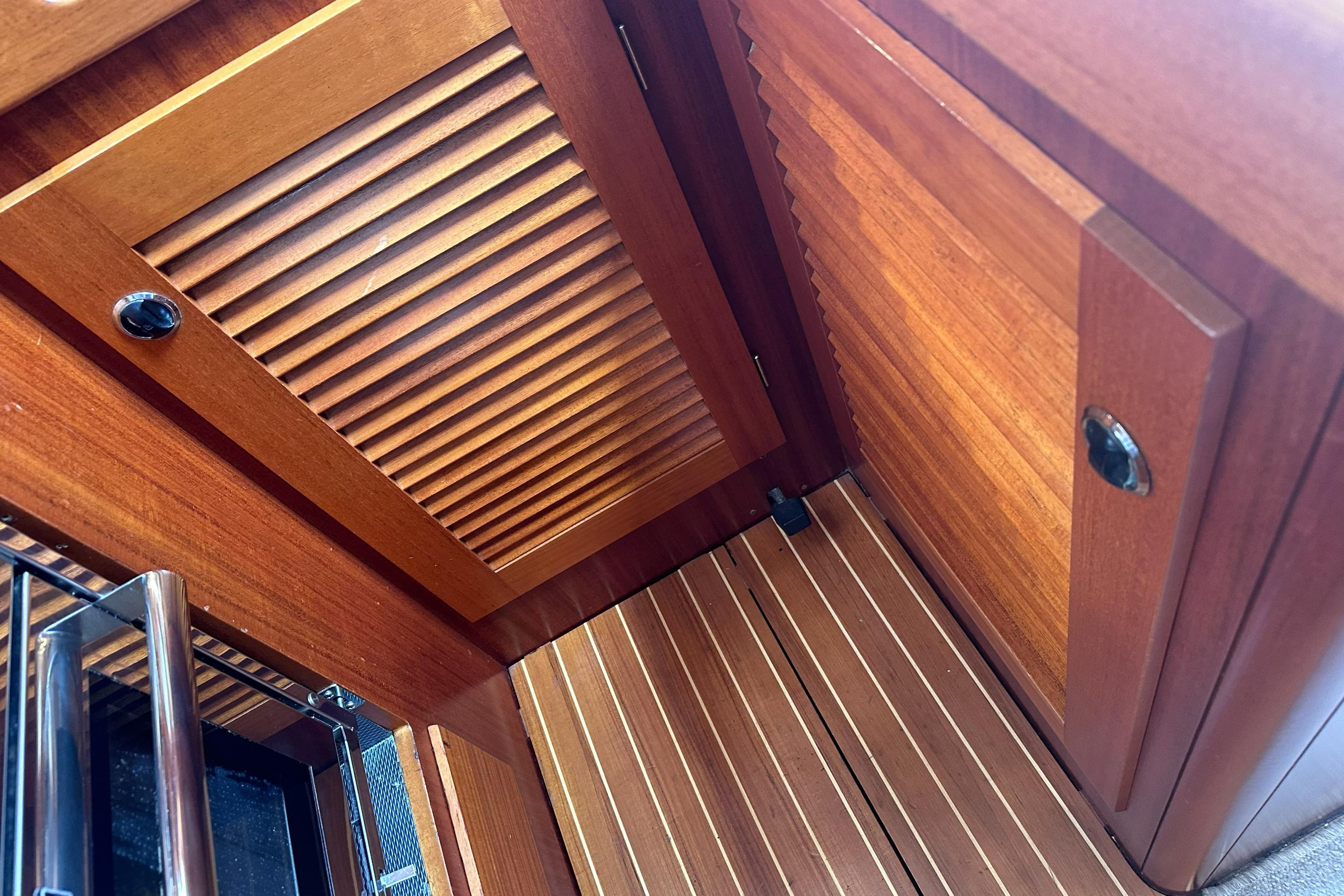 Interior woodwork of a 2000 Hallberg-Rassy 46 yacht, featuring elegant louvered panels.