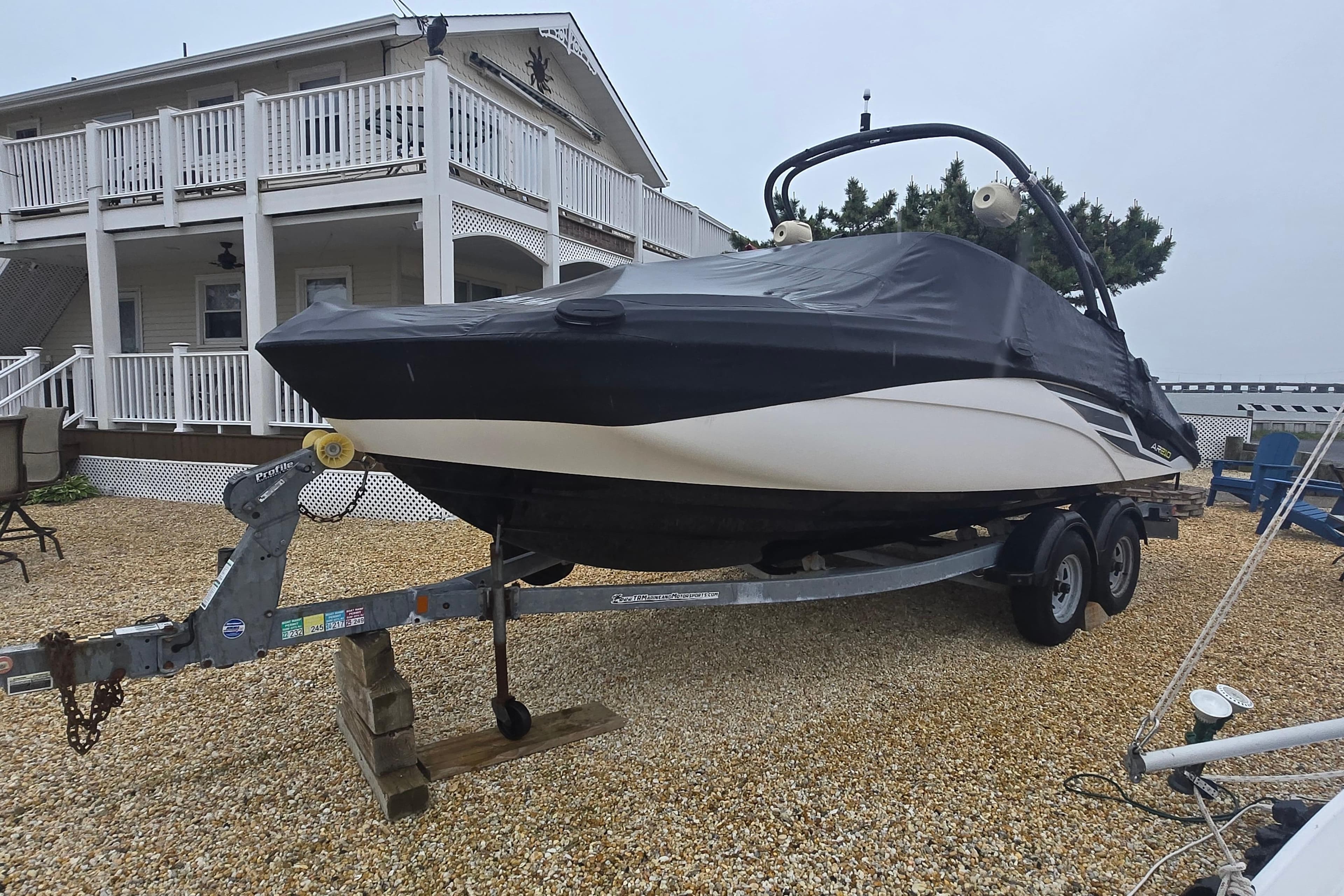 2018 Yamaha AR210 boat on trailer, covered, near a large house.