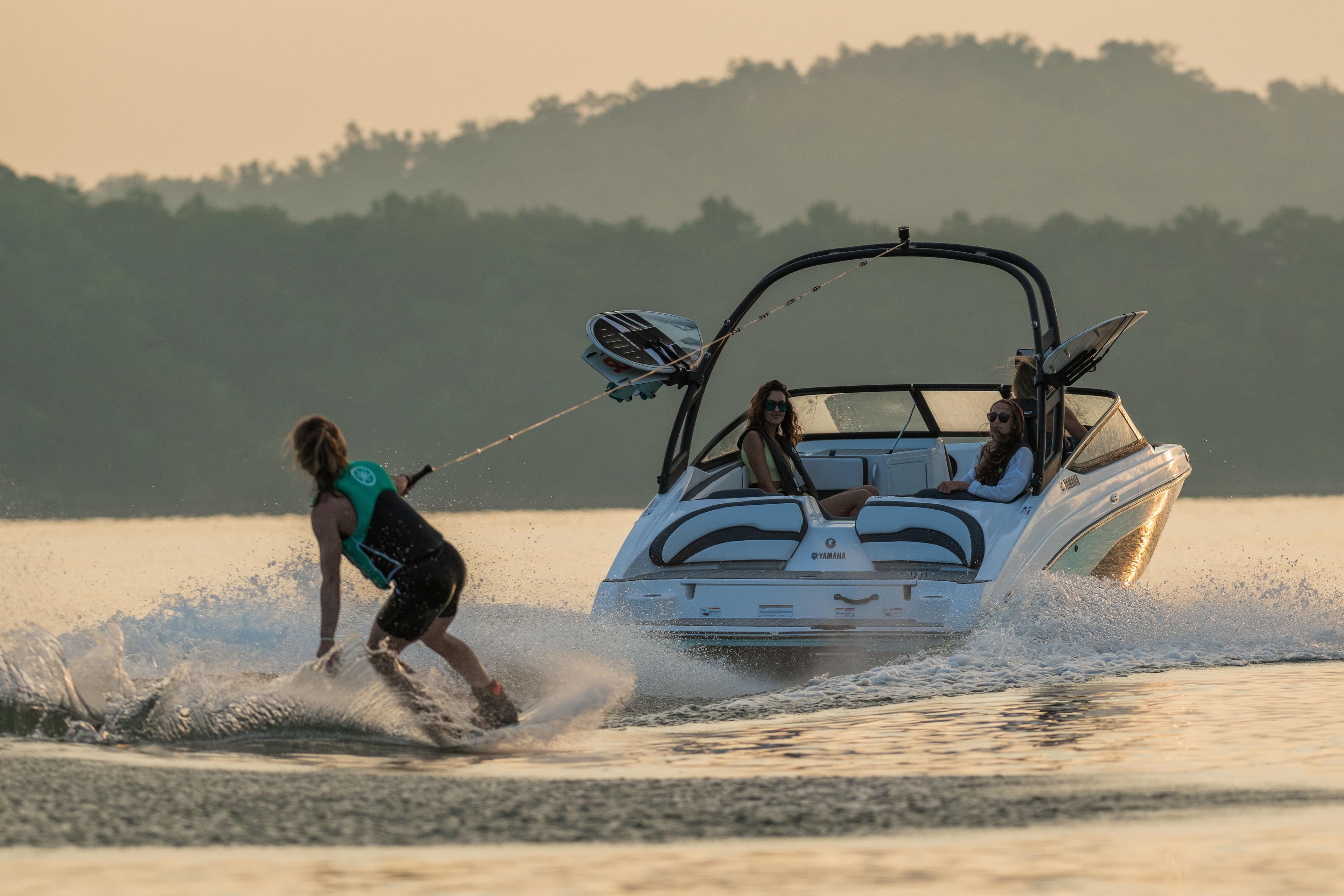 Manufacturer Provided Image: 2026 Yamaha AR195 boat towing a wakeboarder on a serene lake at sunset.