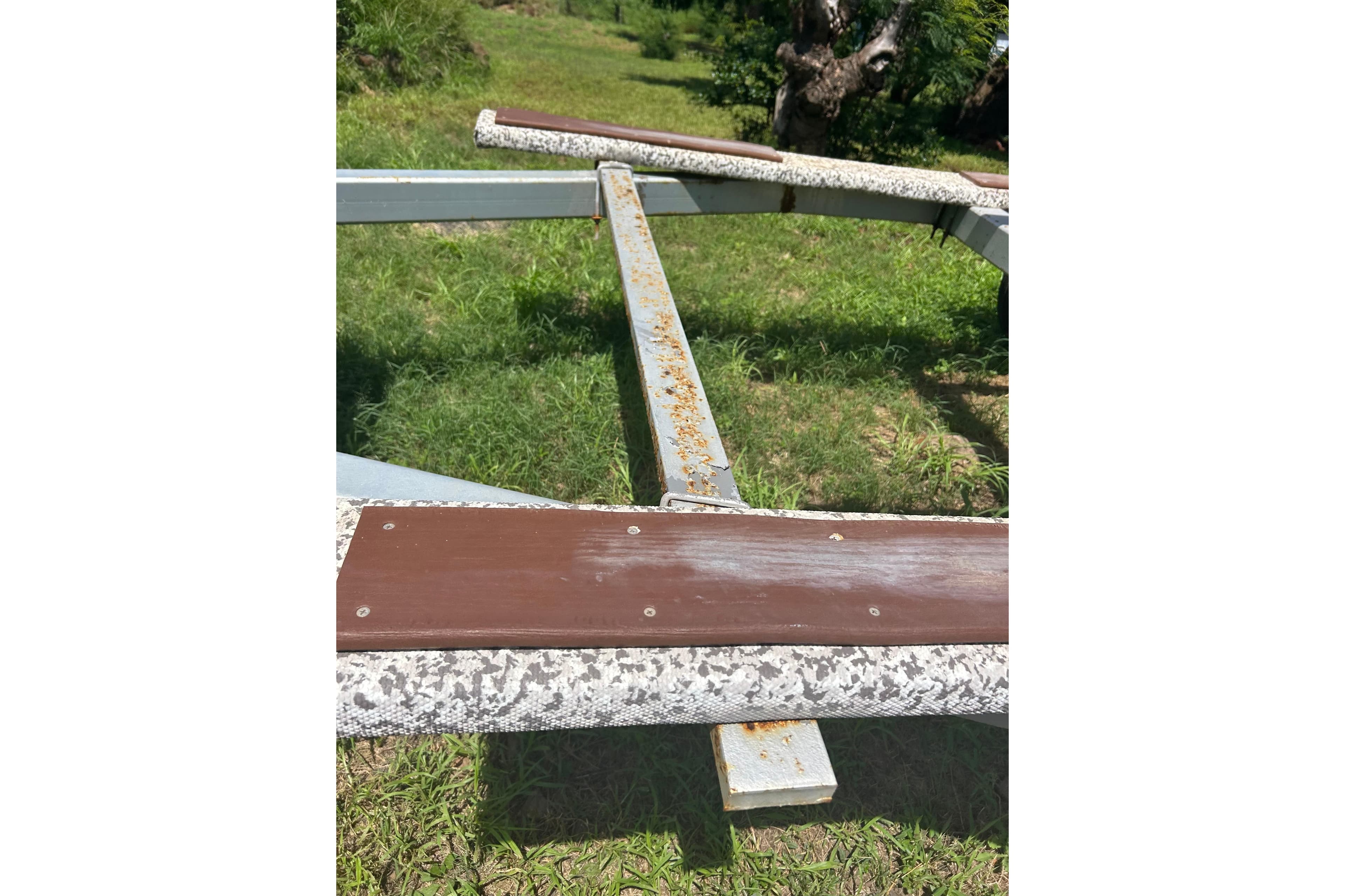 Trailer frame for 2004 Glacier Bay 2270 Isle Runner on grass.