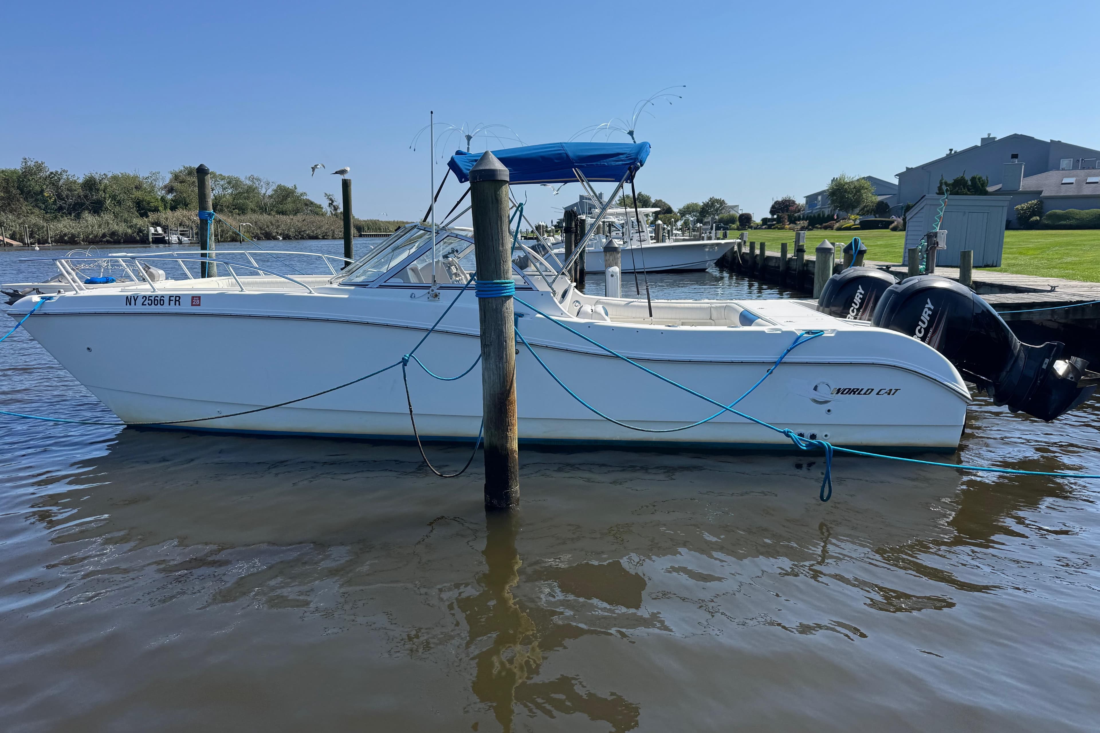 2000 World Cat 246 DC boat docked in a serene marina setting.