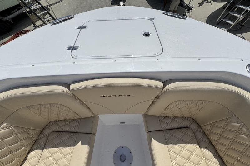 2026 Southport 33 DC boat interior with beige quilted seating and storage hatch.