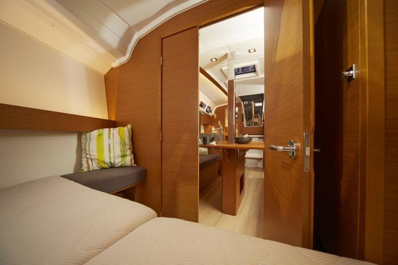 Manufacturer Provided Image: Interior cabin of 2019 Jeanneau Sun Odyssey 349 sailboat, featuring cozy bedding and wooden finishes.