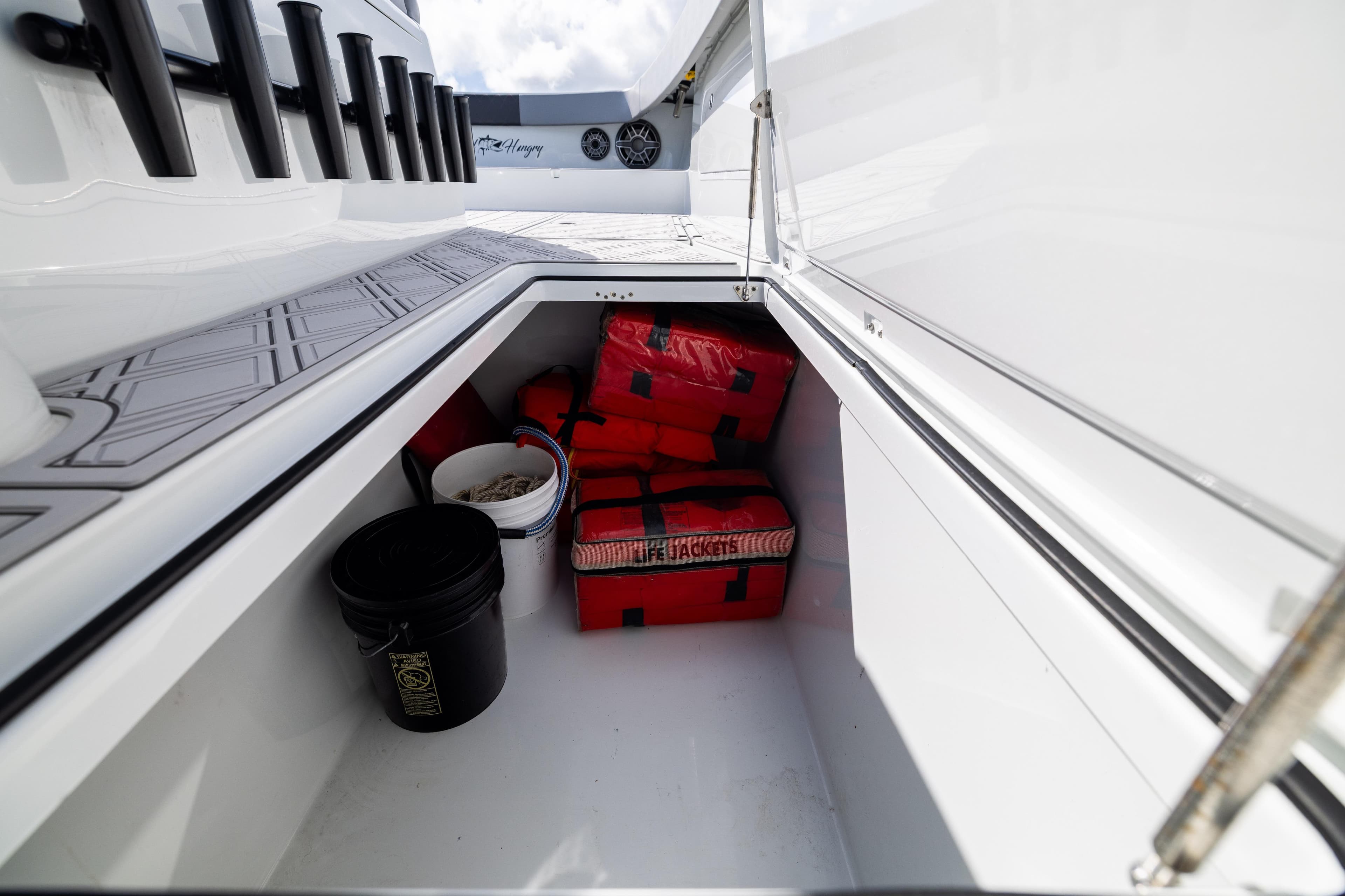 Storage compartment on a 2023 Freeman 47 boat with life jackets and buckets.