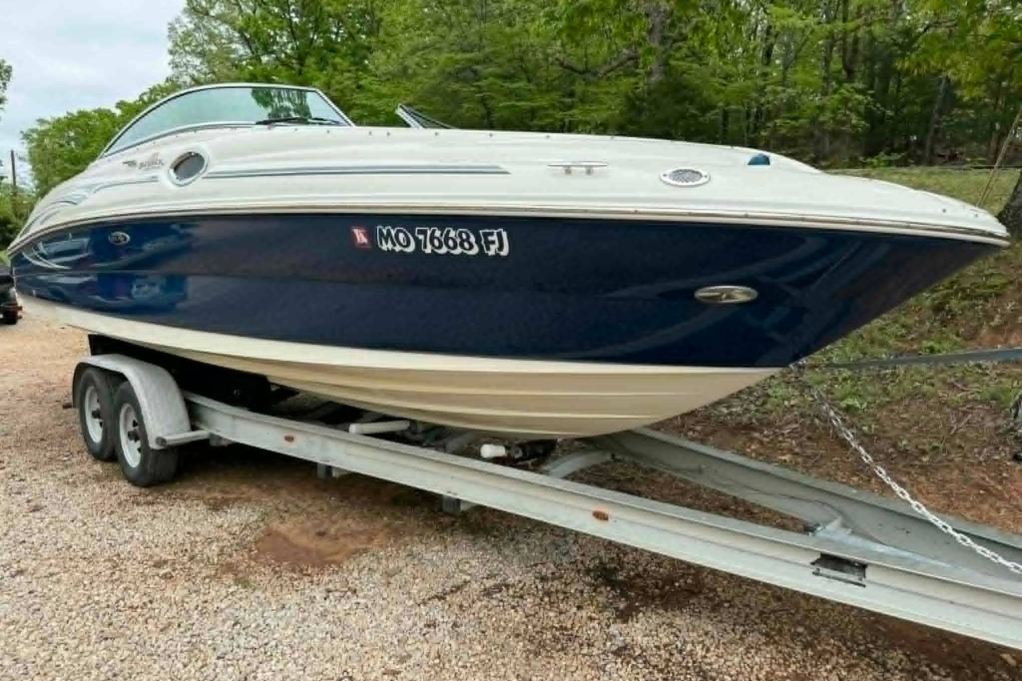 2006 Sea Ray 240 Sundeck boat on trailer, parked outdoors.
