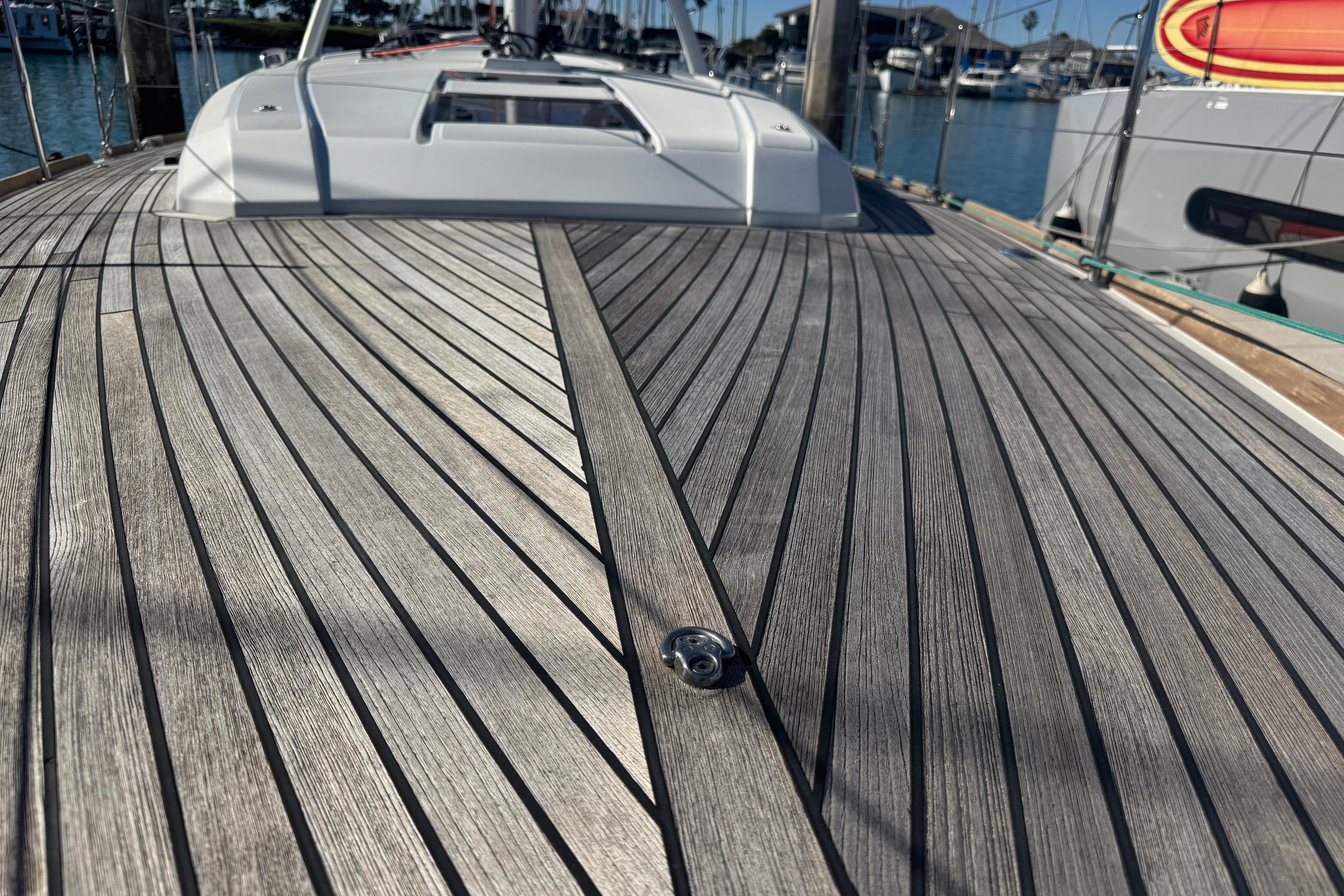 Deck of 2023 Beneteau Oceanis 38.1 sailboat with sleek wooden finish in marina.