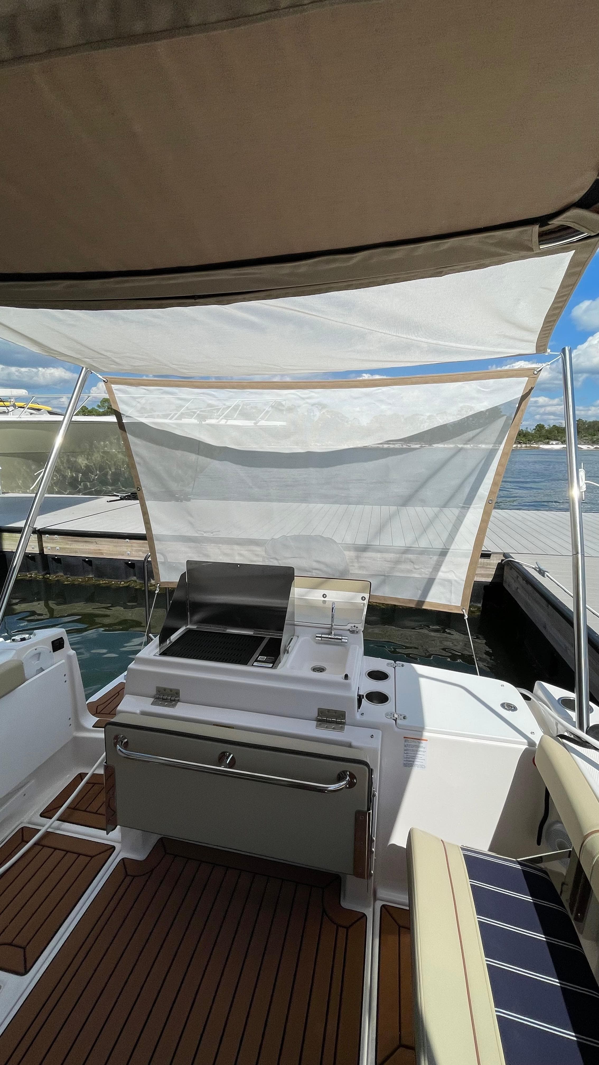 2026 Ranger Tugs R-27 boat with outdoor grill and seating, docked by the water.
