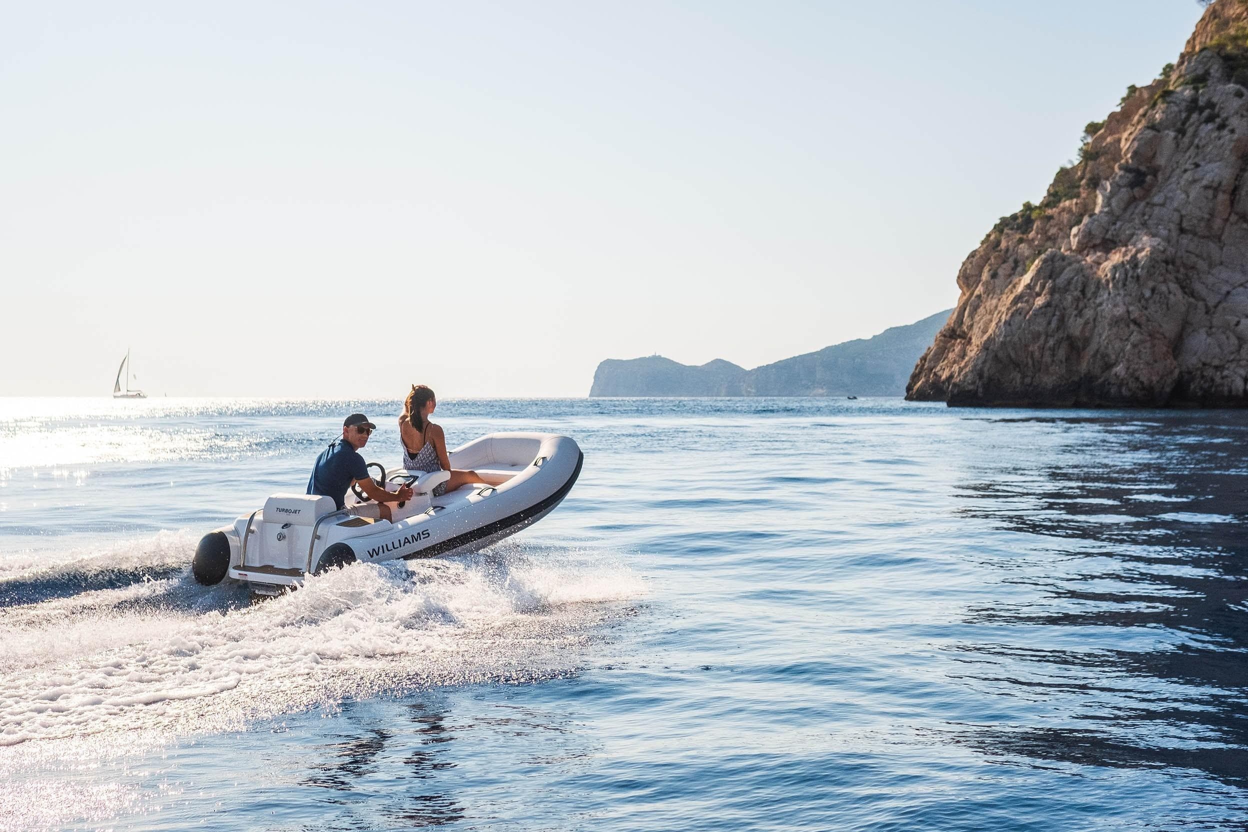 2026 Williams Jet Tenders Turbojet 325 cruising near rocky coastline.