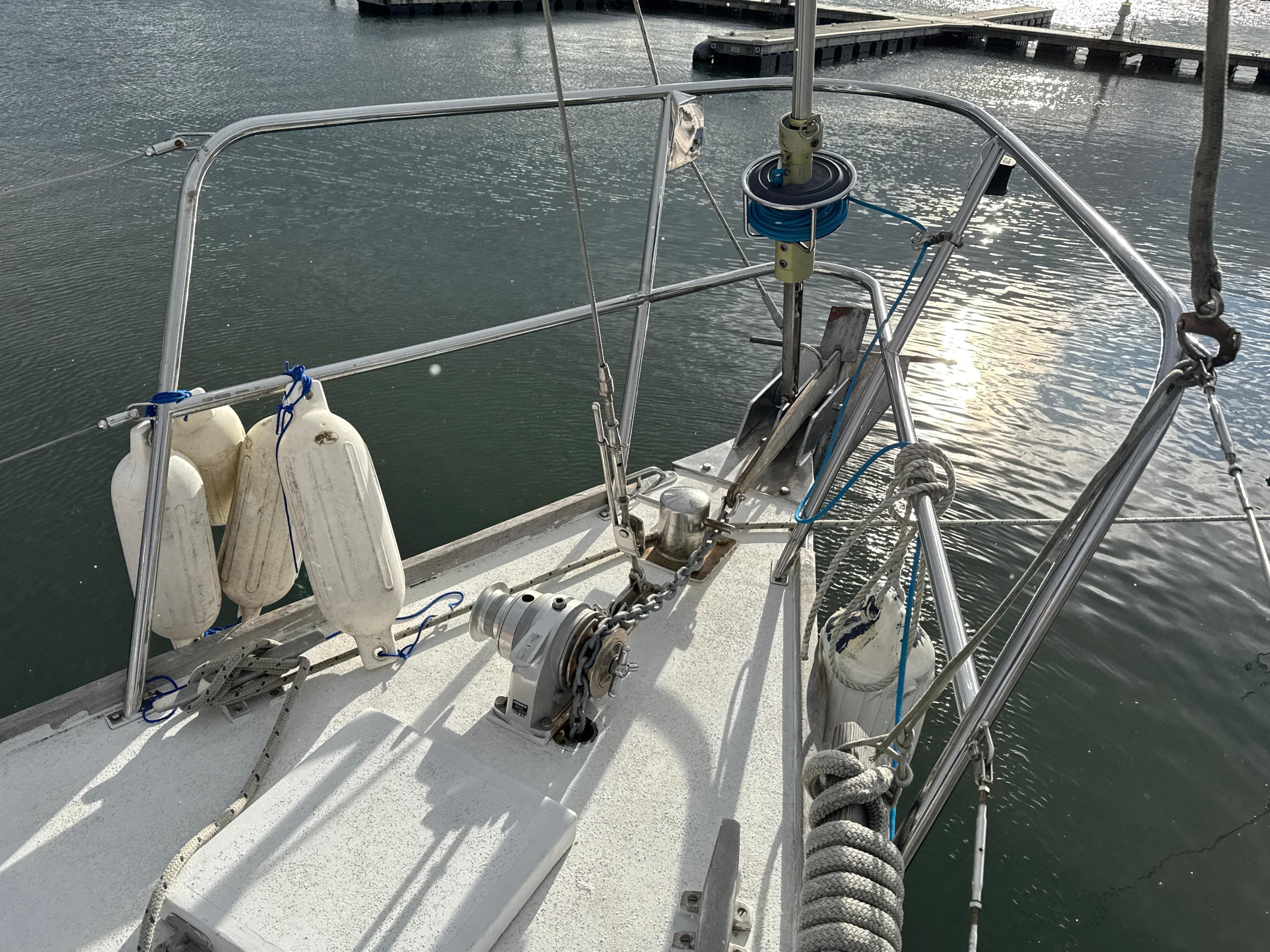 Bow of 1980 Bruce Roberts Mauritius 43 sailboat with fenders and winch in marina.